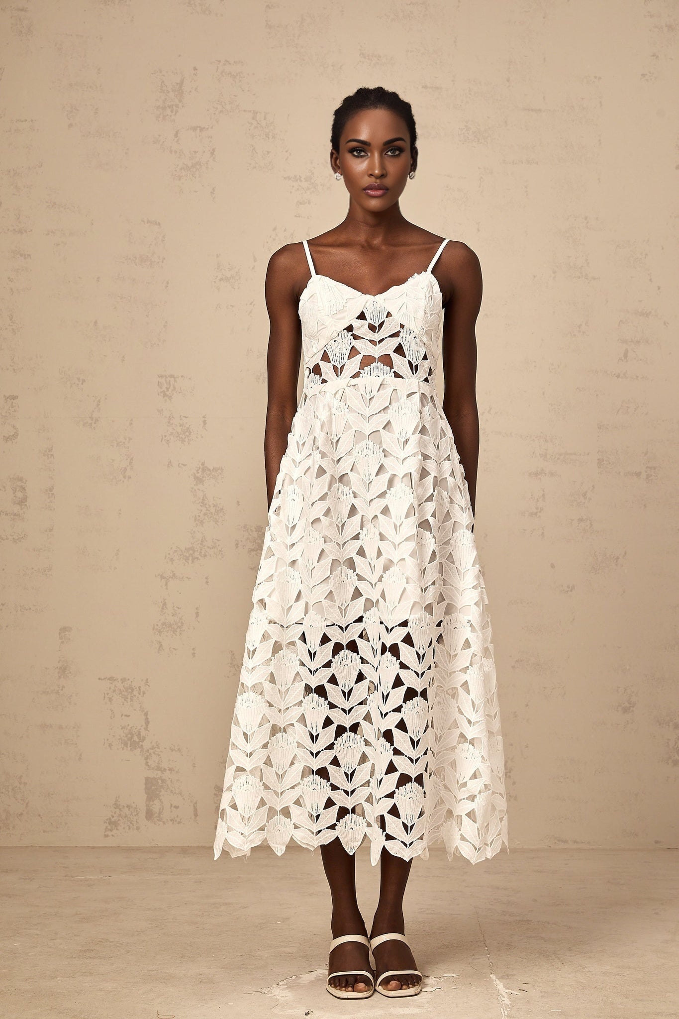 A white lace midi dress with cutout details featuring a delicate floral pattern and fitted silhouette