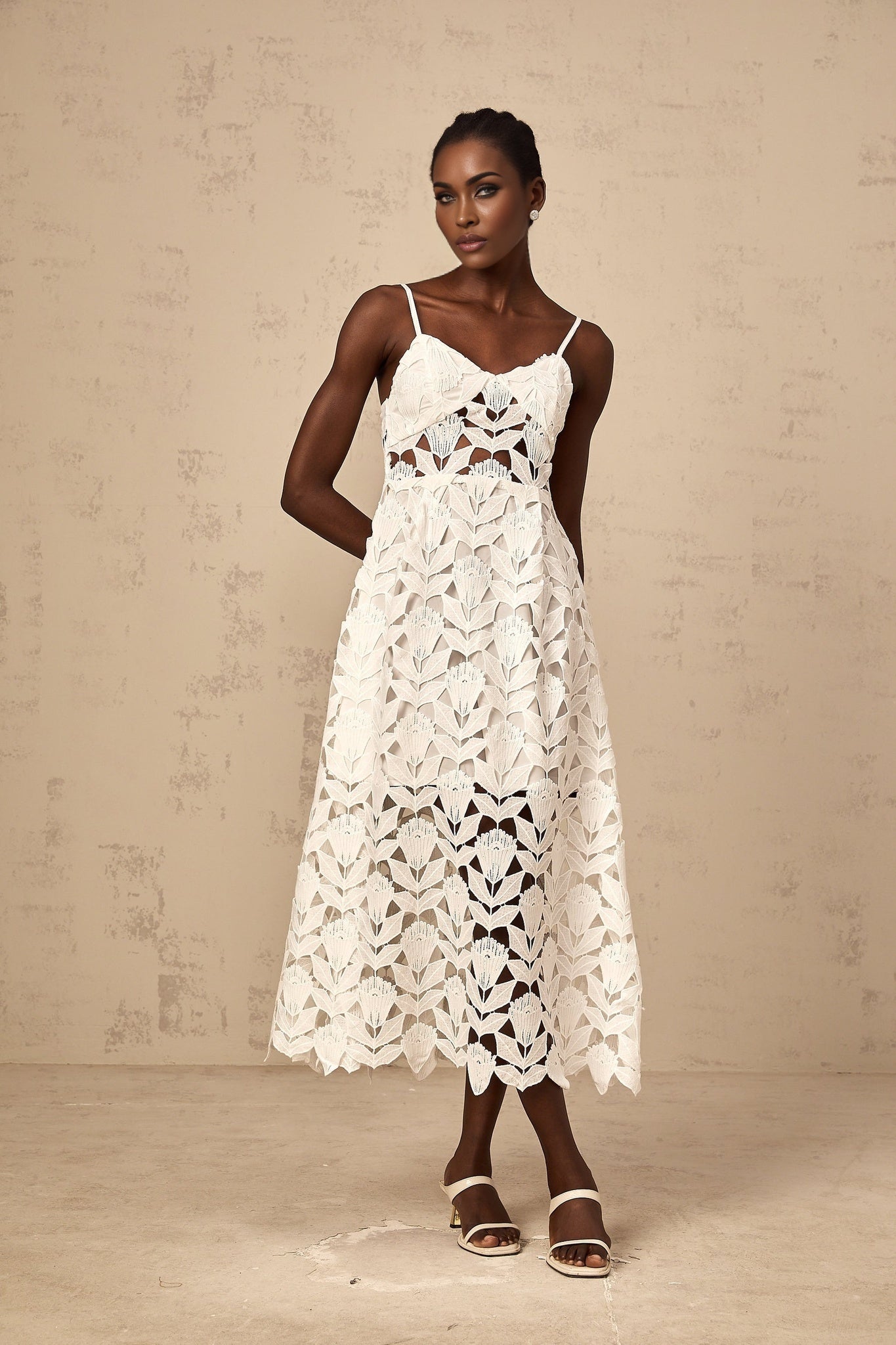 A white lace midi dress with cutout details named Delphine featuring a delicate floral pattern and a fitted silhouette