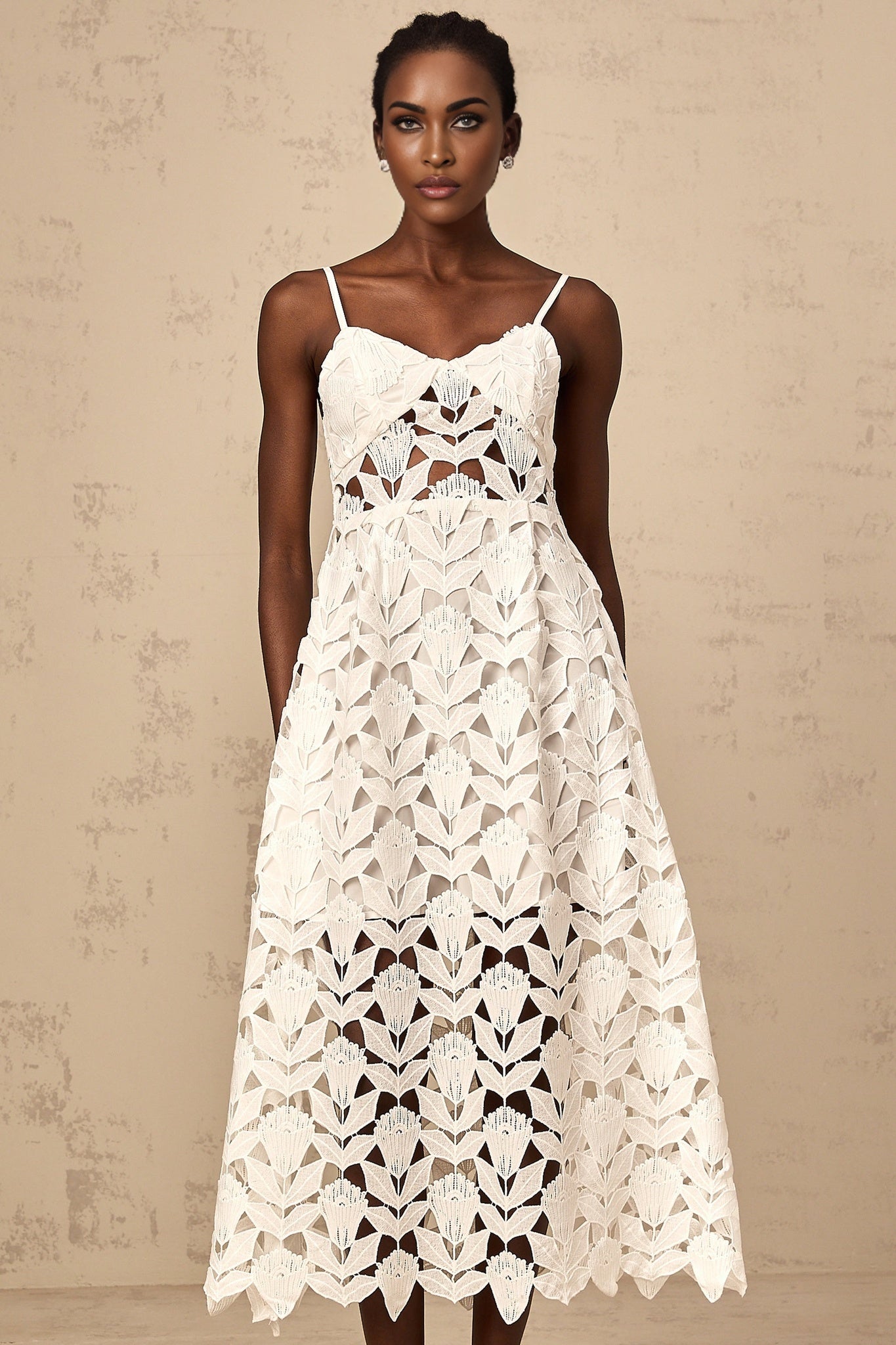 A white lace midi dress with cutout details named Delphine featuring a delicate floral pattern and an elegant silhouette