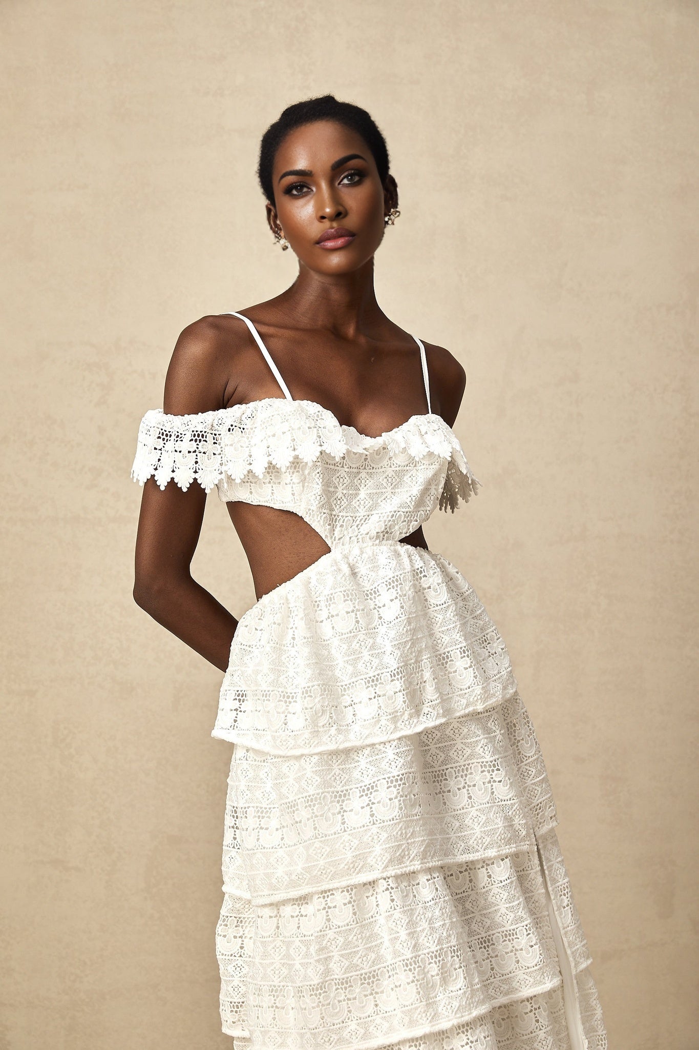 A white lace midi dress with open work detailing named Genevieve on a plain background