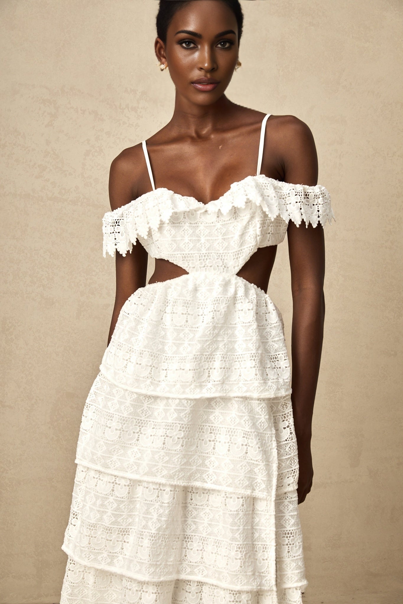 A white lace midi dress with openwork details named Genevieve worn by a model standing against a plain background