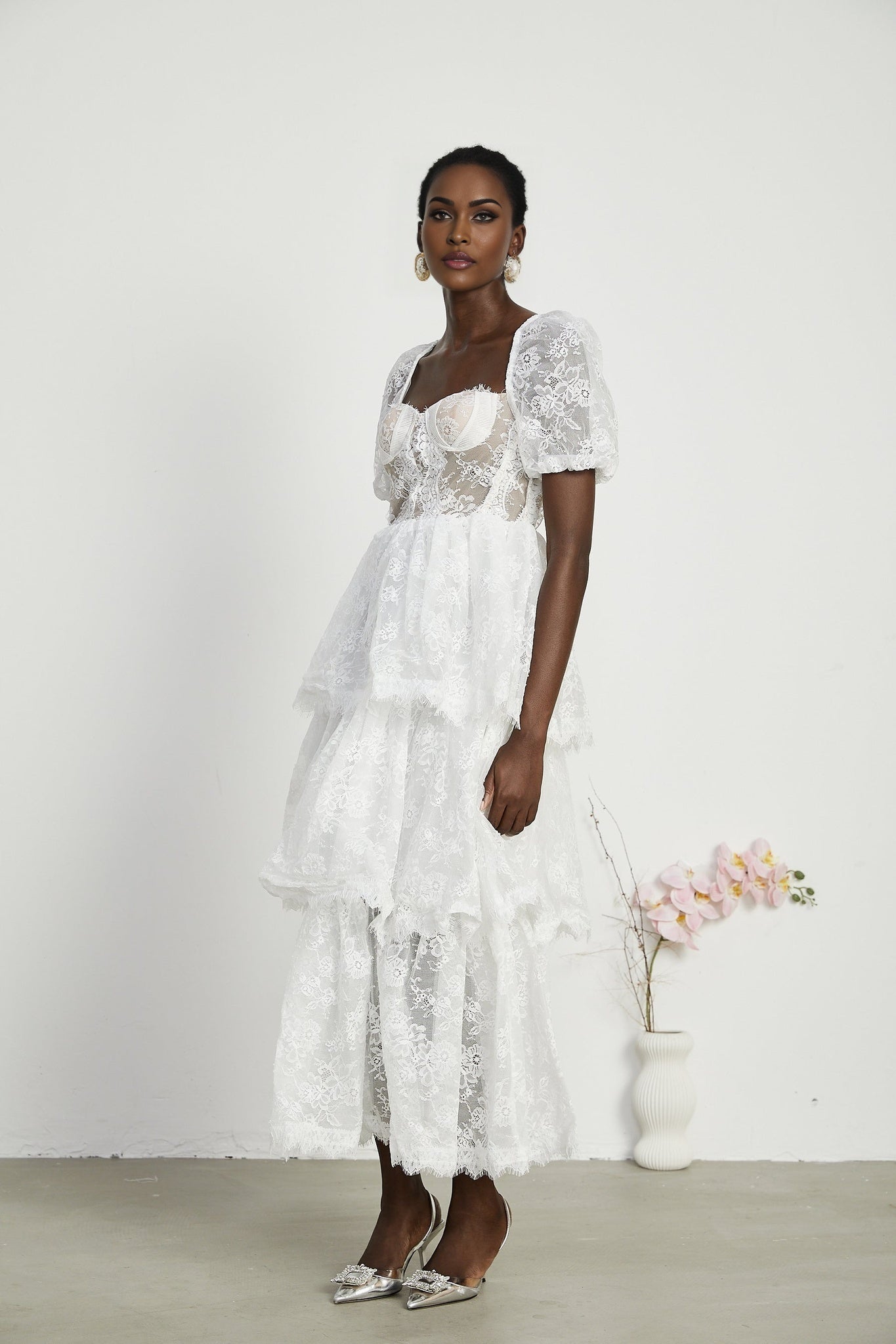 A white lace midi dress with tiered layers by Melisande