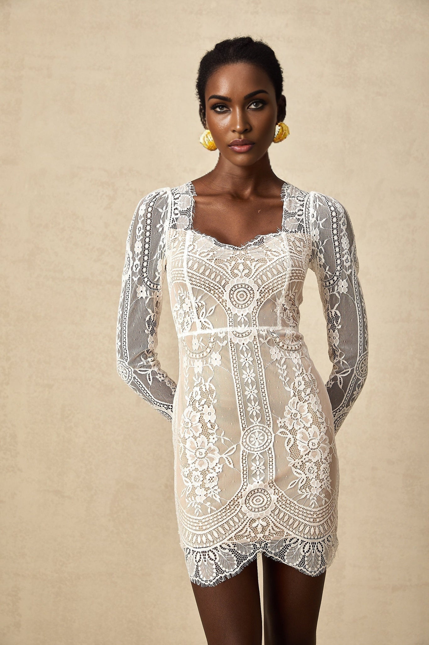 A white lace mini dress with scalloped hem and delicate floral pattern