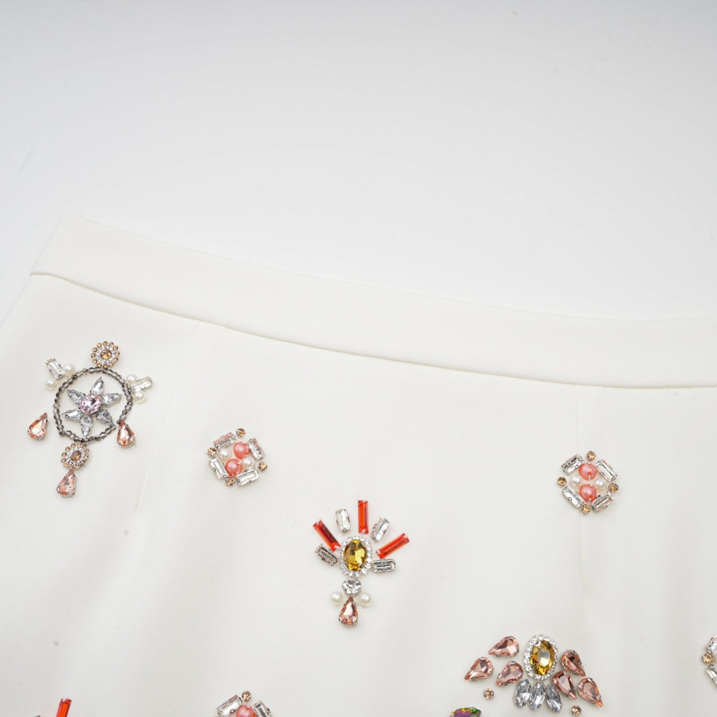 A white matching set consisting of a top and skirt adorned with crystal embellishments named Jeanne