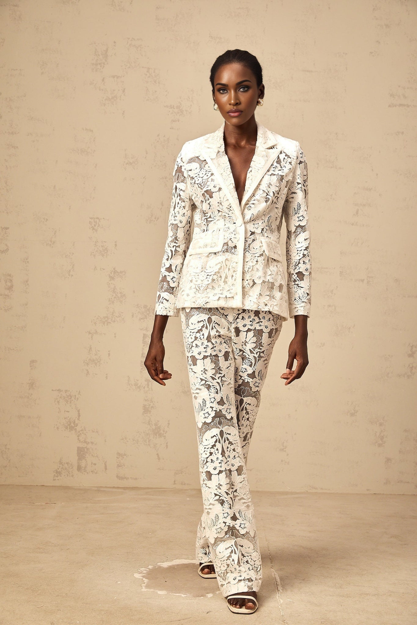 A white matching set featuring a blazer and trousers made of tulle with sequined flower embroidery The blazer and trousers are adorned with delicate floral patterns created using white sequins on sheer tulle fabric