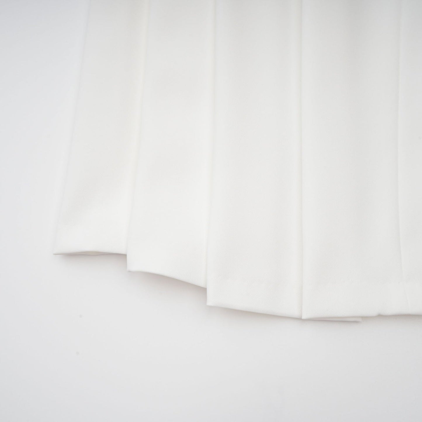 A white matching set featuring a creased top and trousers worn by a model standing against a plain background