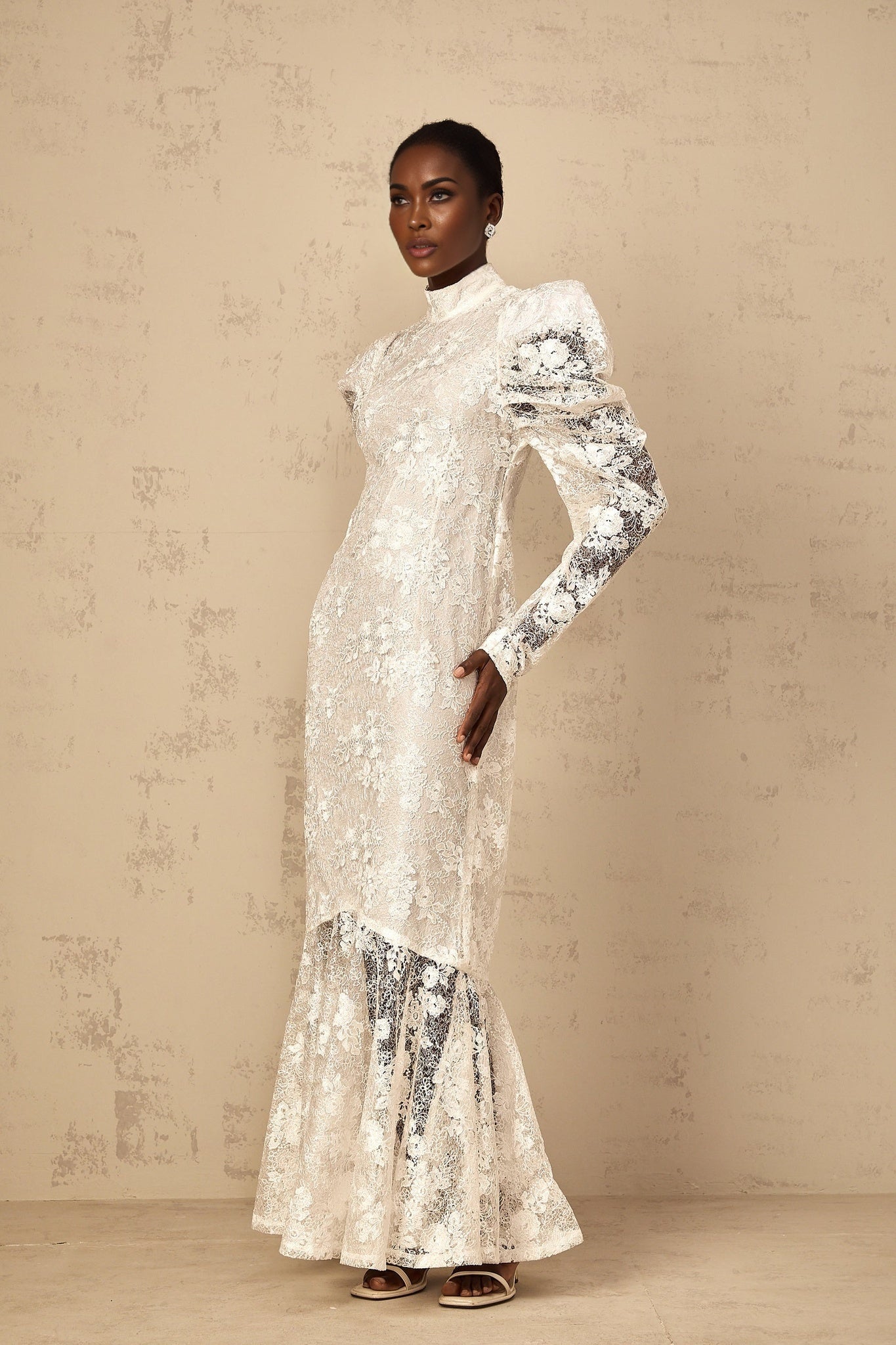 A white mermaid style maxi dress with floral lace detailing named Pauline worn by a female model against a plain background