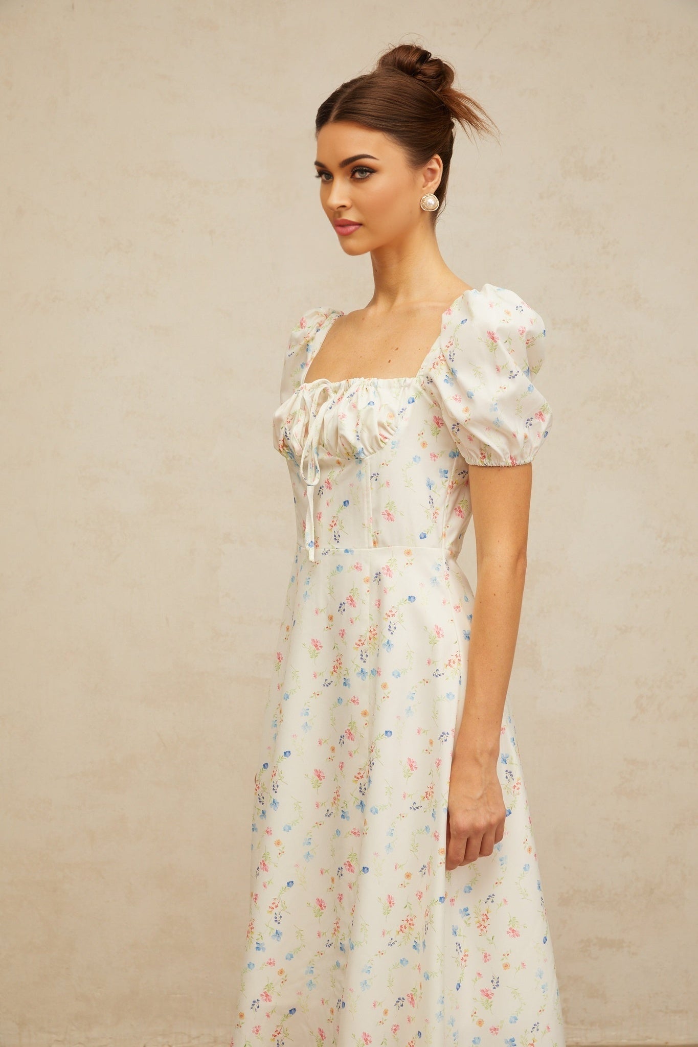 A white midi dress with a floral print pattern and flared skirt design worn by a model against a plain background