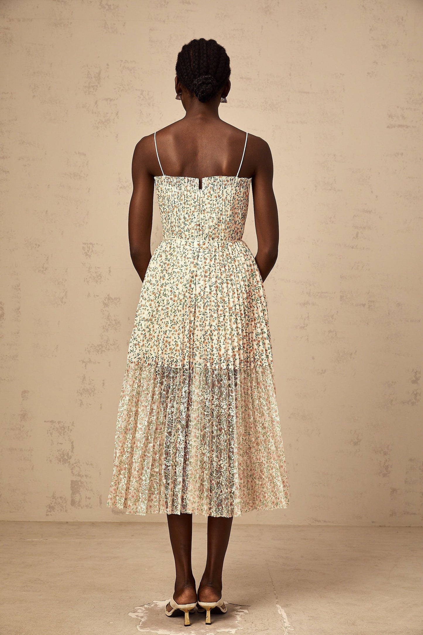 A white midi dress with a floral print pattern and pleated design featuring a flowing silhouette and delicate details