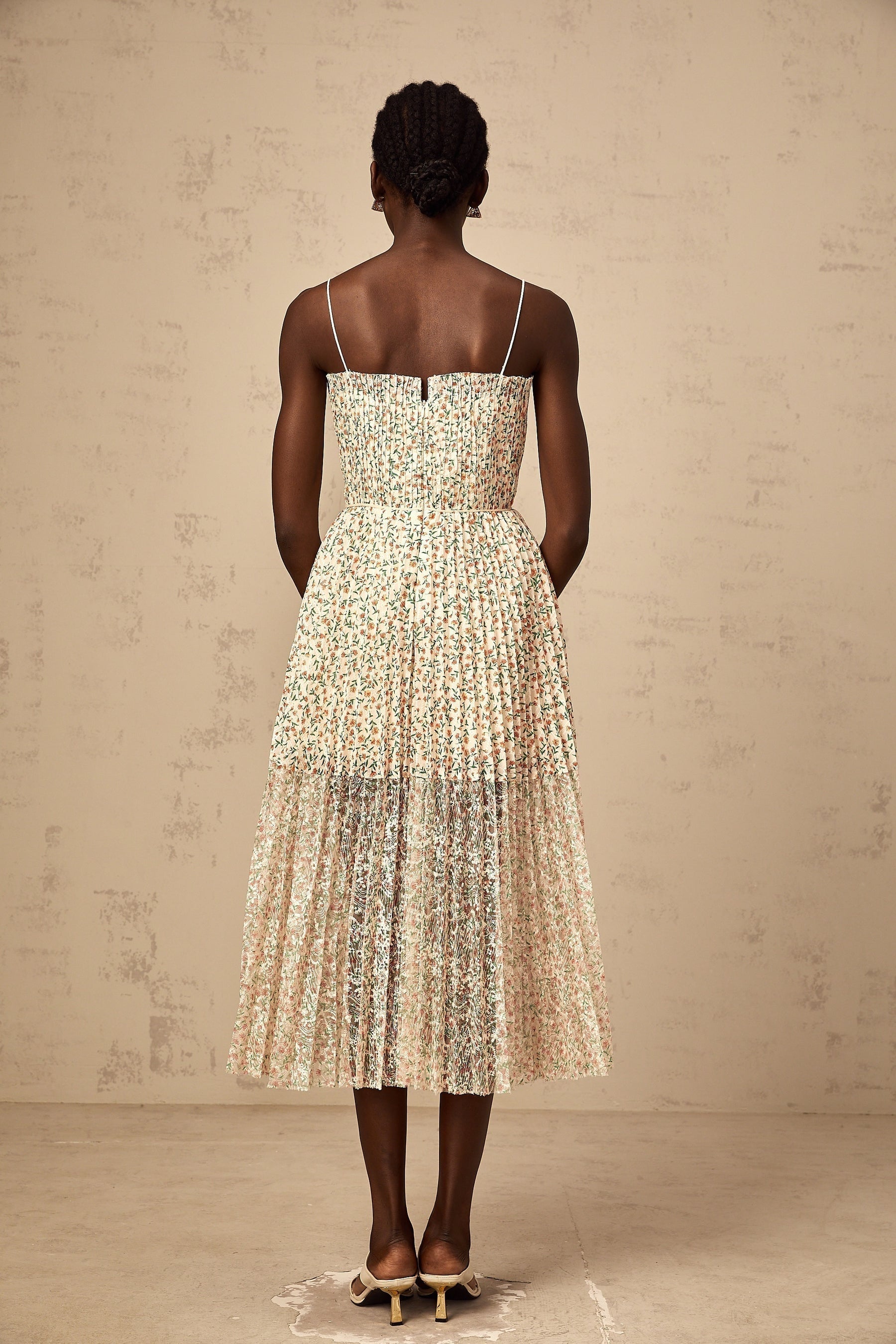 A white midi dress with a floral print pattern and pleated design featuring a flowing silhouette and delicate details