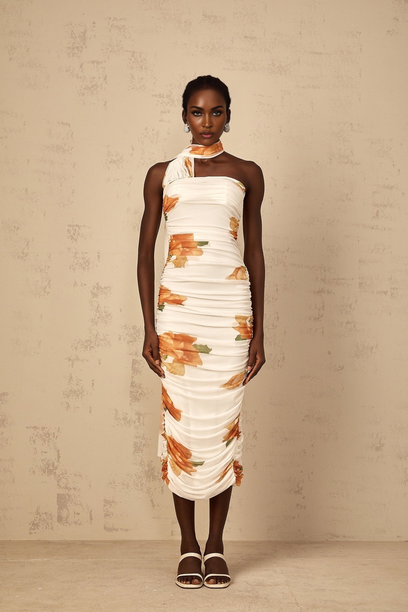 A white midi dress with a floral print pattern and ruched tulle fabric featuring a feminine silhouette