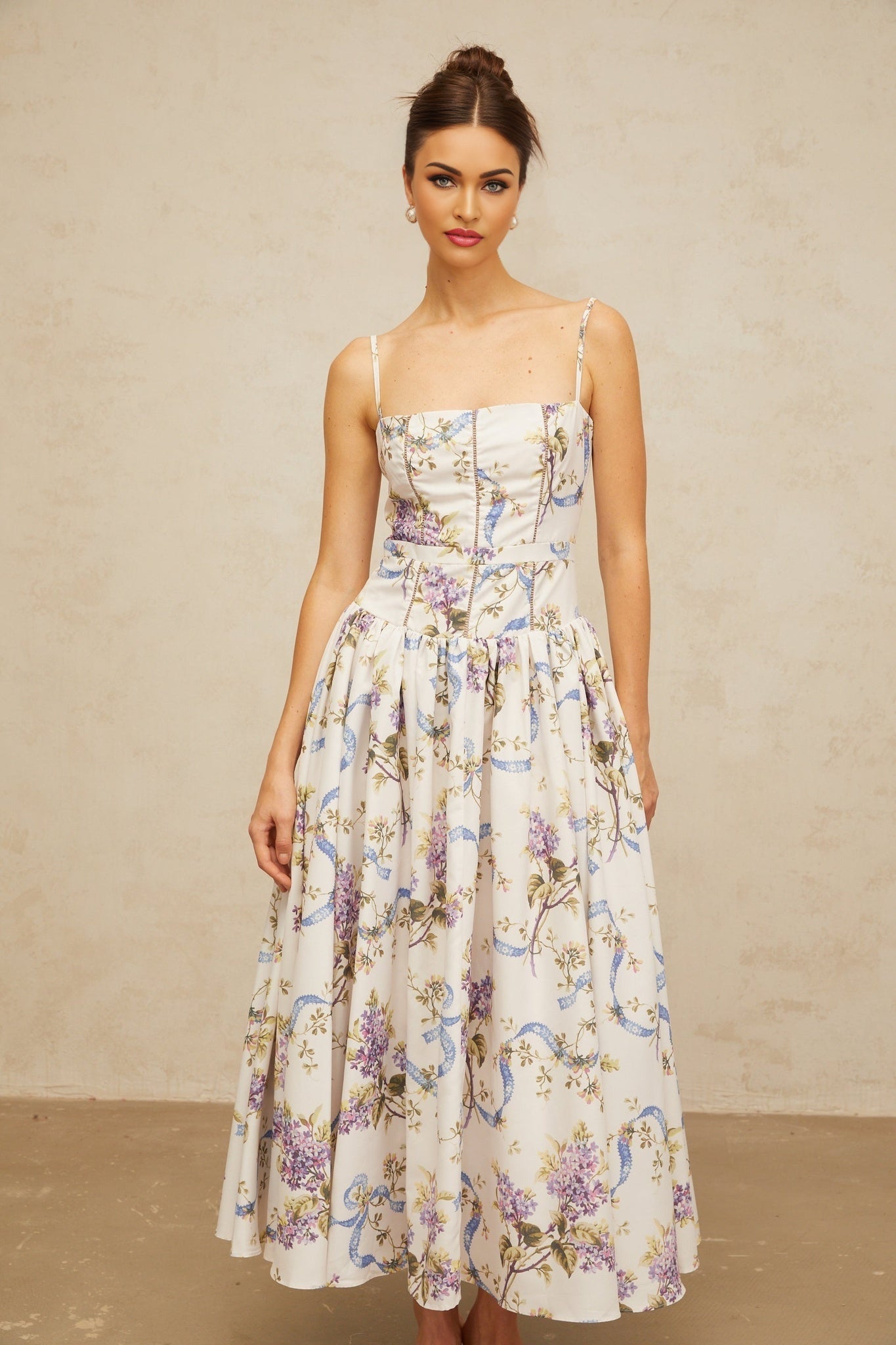 A white midi dress with a floral print pattern covering the fabric The dress features a feminine and elegant design suitable for various occasions