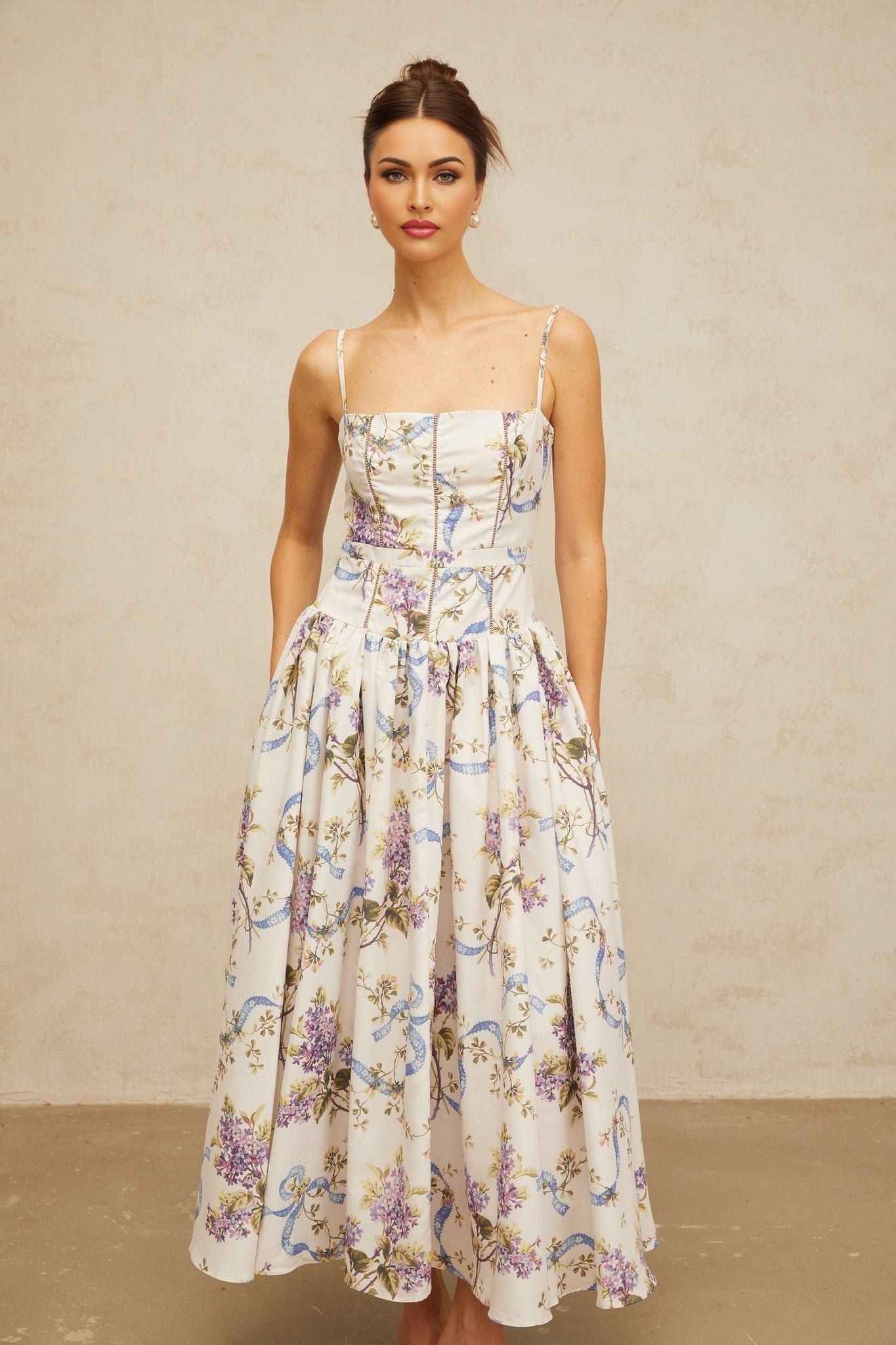 A white midi dress with a floral print pattern covering the fabric The dress features a feminine silhouette and falls to mid calf length