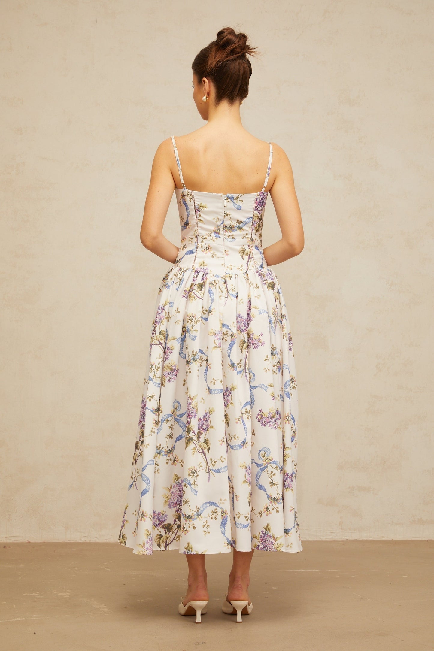A white midi dress with a floral print pattern covering the fabric The dress features a fitted bodice and flowy skirt that falls to mid calf length