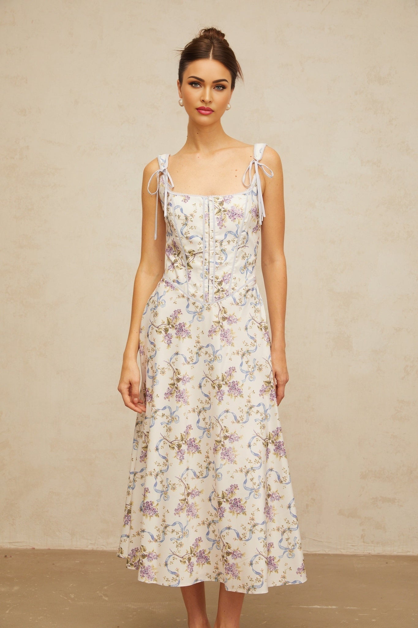 A white midi dress with a floral print pattern featuring a flared silhouette and Bruyere design elements