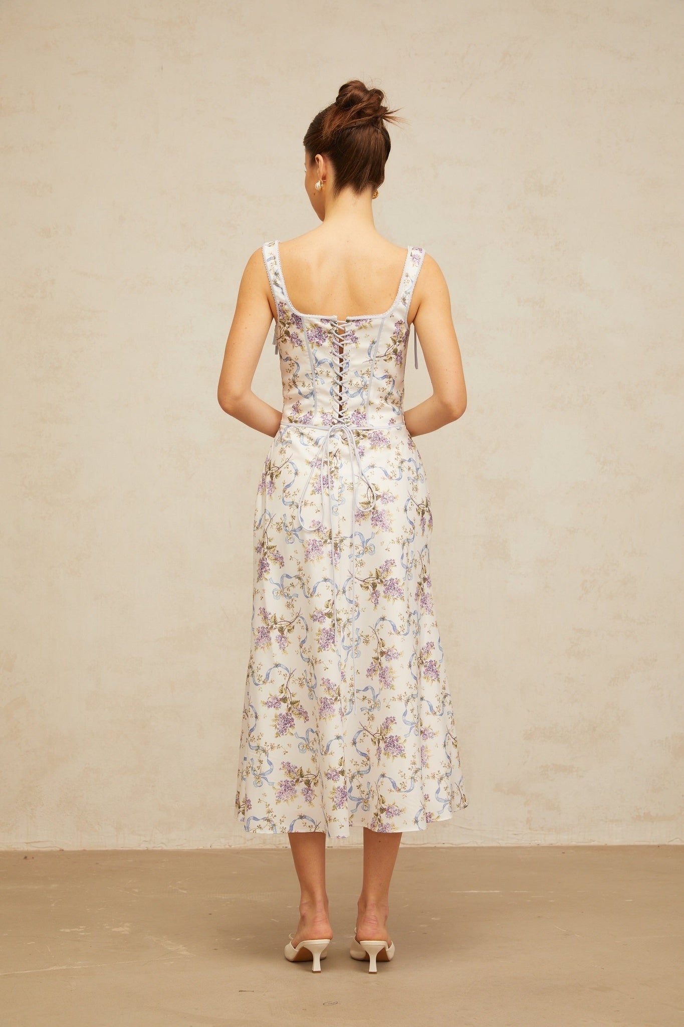 A white midi dress with a floral print pattern featuring a flared skirt and Bruyere design