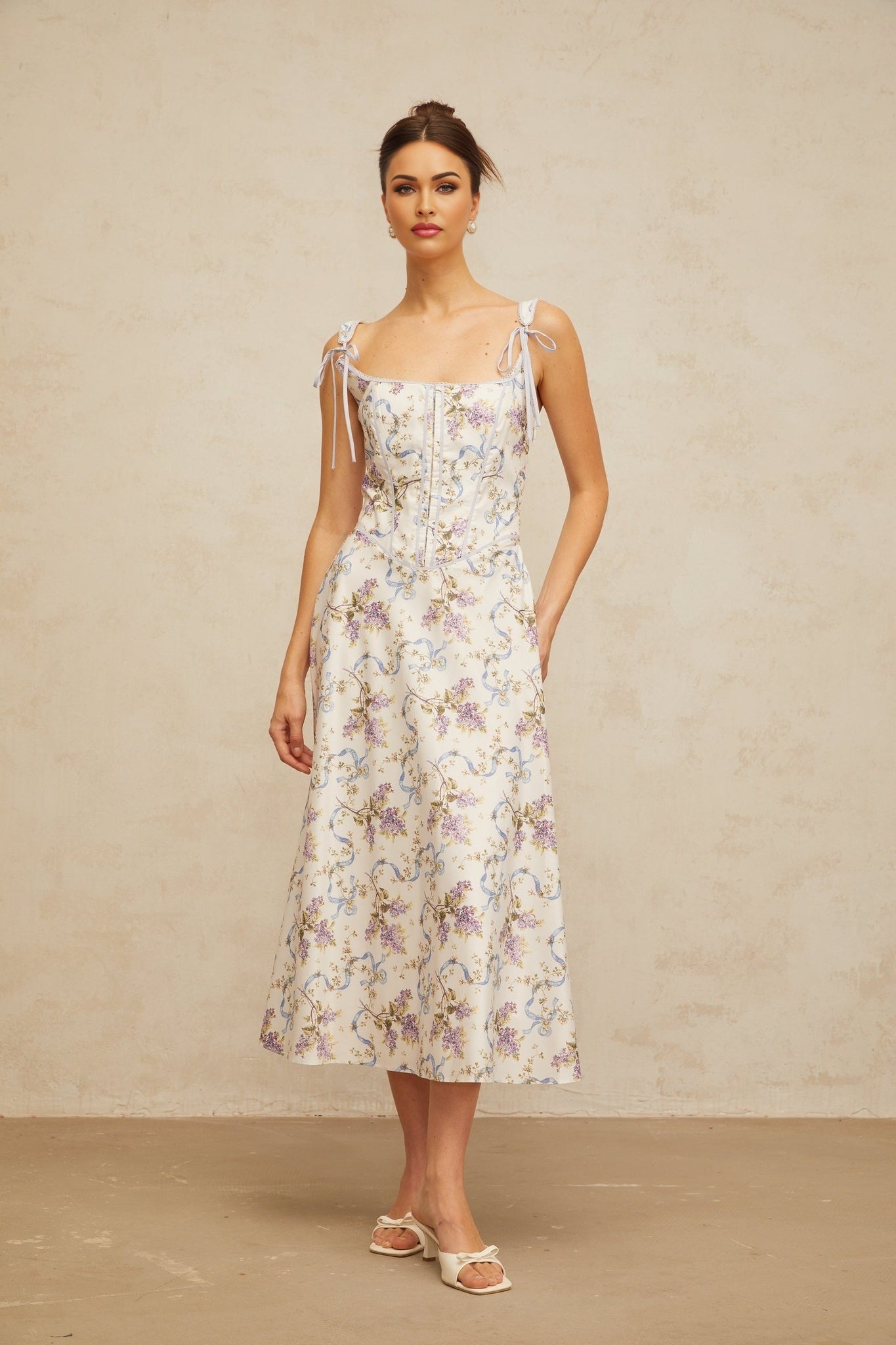 A white midi dress with a floral print pattern featuring a flared skirt and Bruyere design