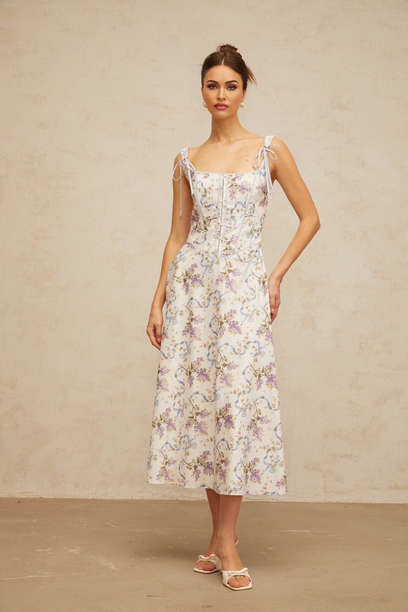 A white midi dress with a floral print pattern featuring a flared skirt and Bruyere design