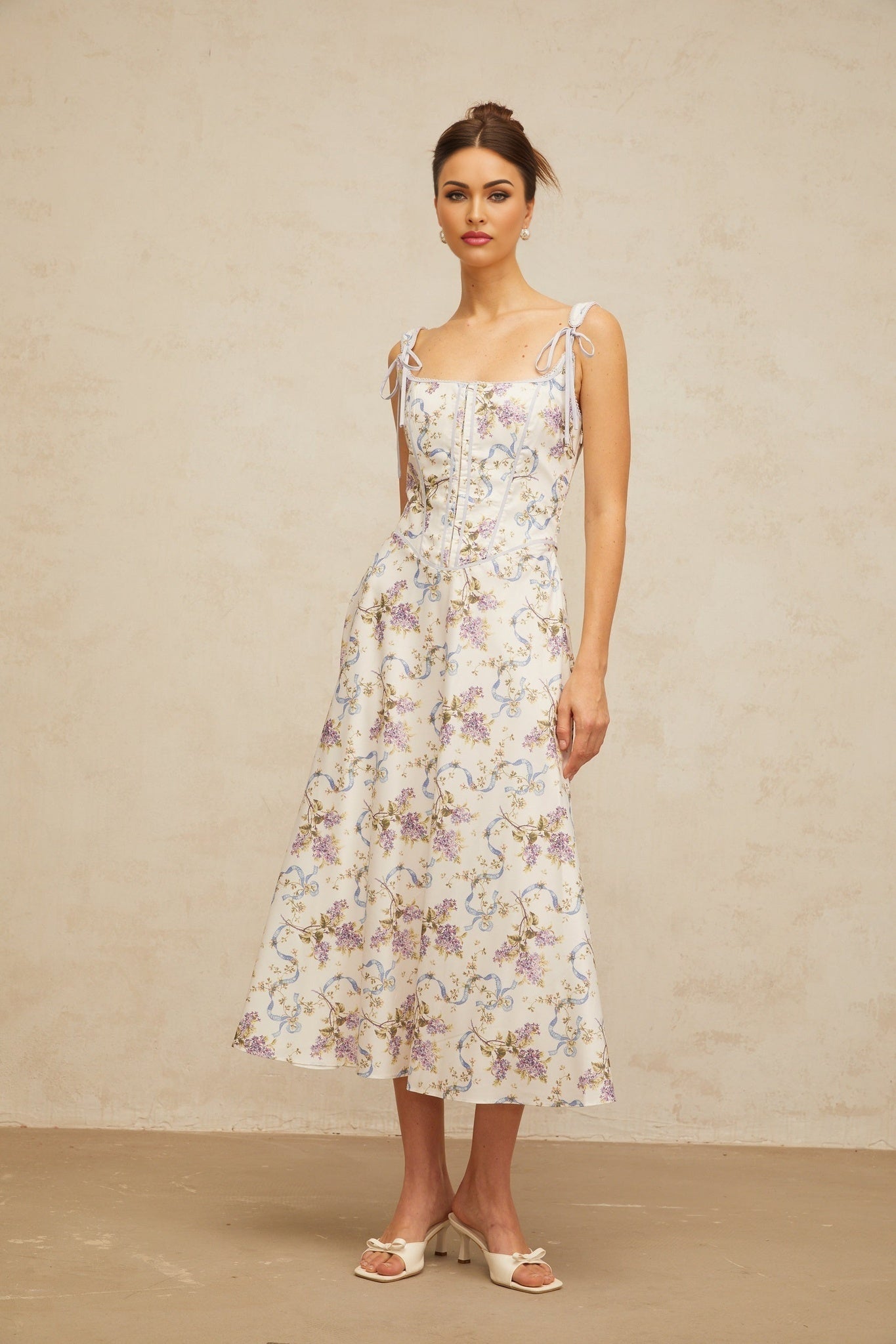 A white midi dress with a floral print pattern featuring a flared skirt and Bruyere design