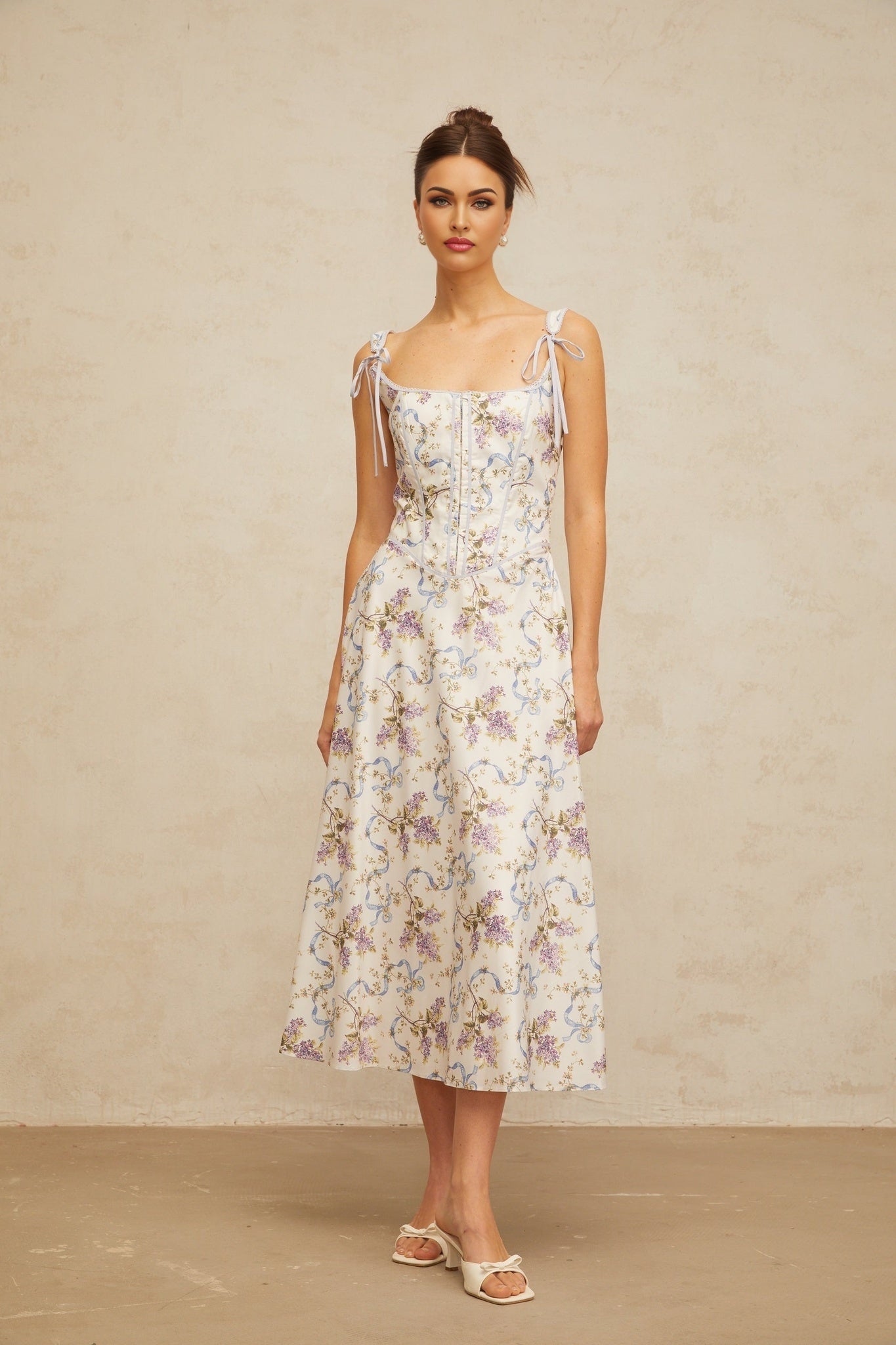 A white midi dress with a floral print pattern featuring a flared skirt design and Bruyere branding