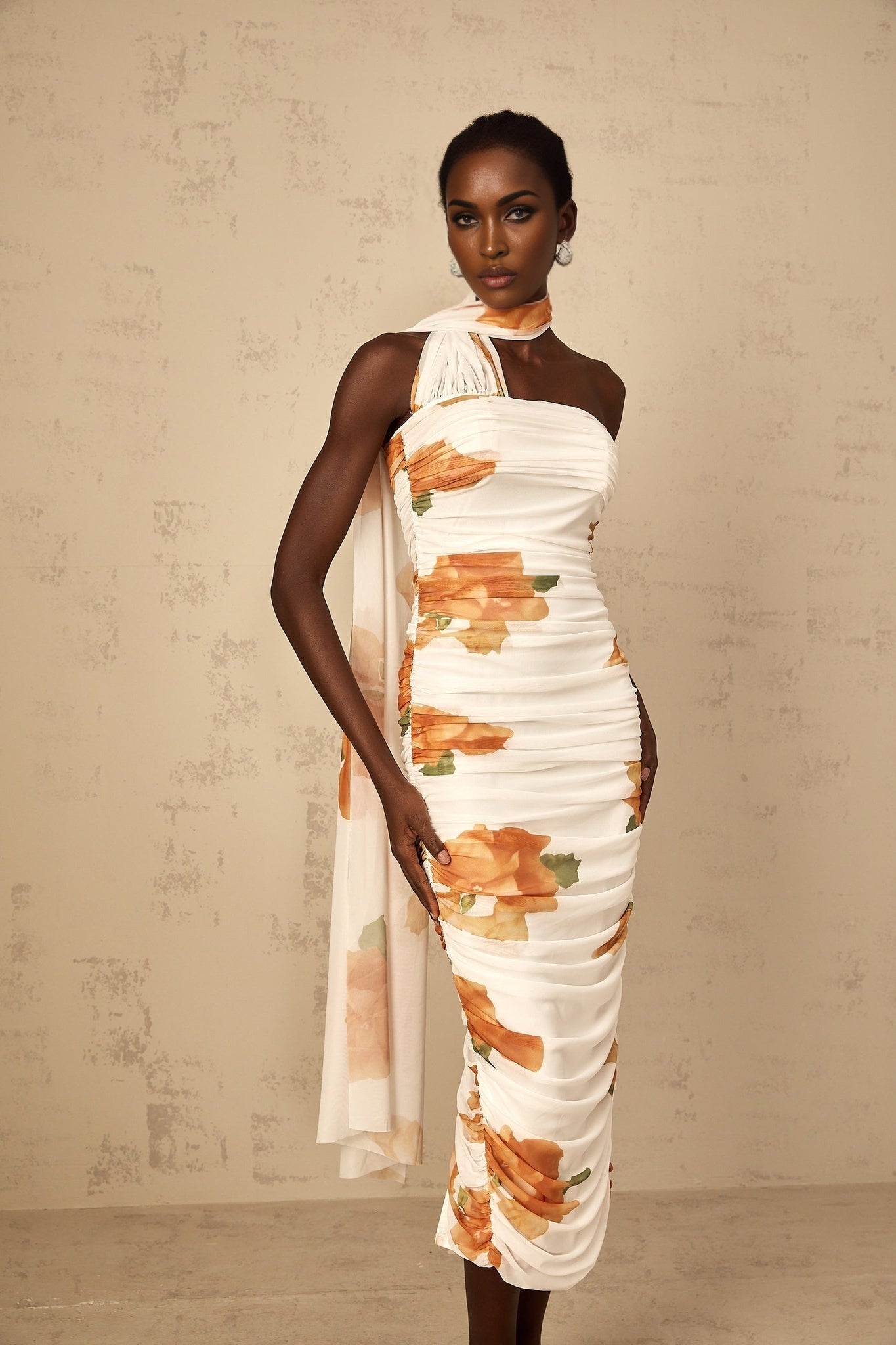A white midi dress with a floral print pattern featuring ruched tulle fabric and a fitted silhouette