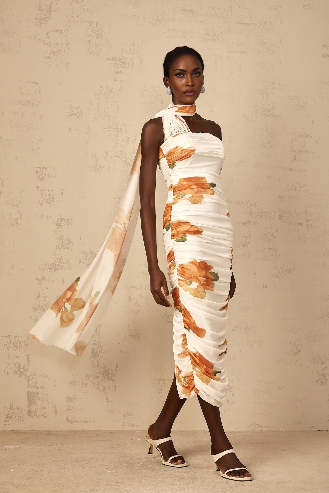 A white midi dress with a floral print pattern made of ruched tulle fabric featuring a feminine and delicate design