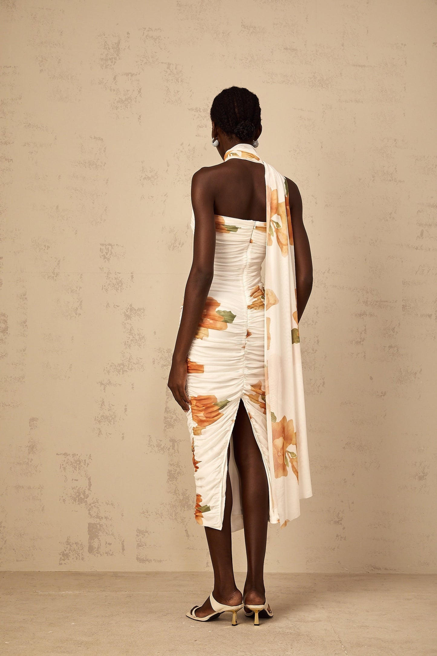 A white midi dress with a floral print pattern made of ruched tulle fabric featuring a feminine and romantic design
