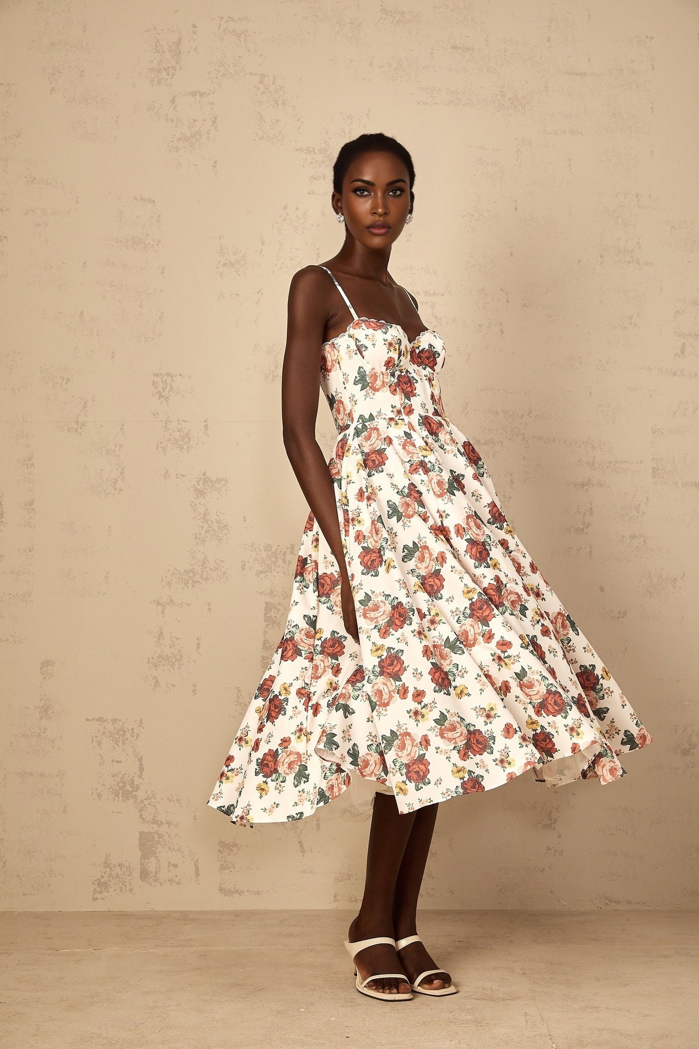 A white midi dress with a rose print pattern featuring flounced details worn by a woman