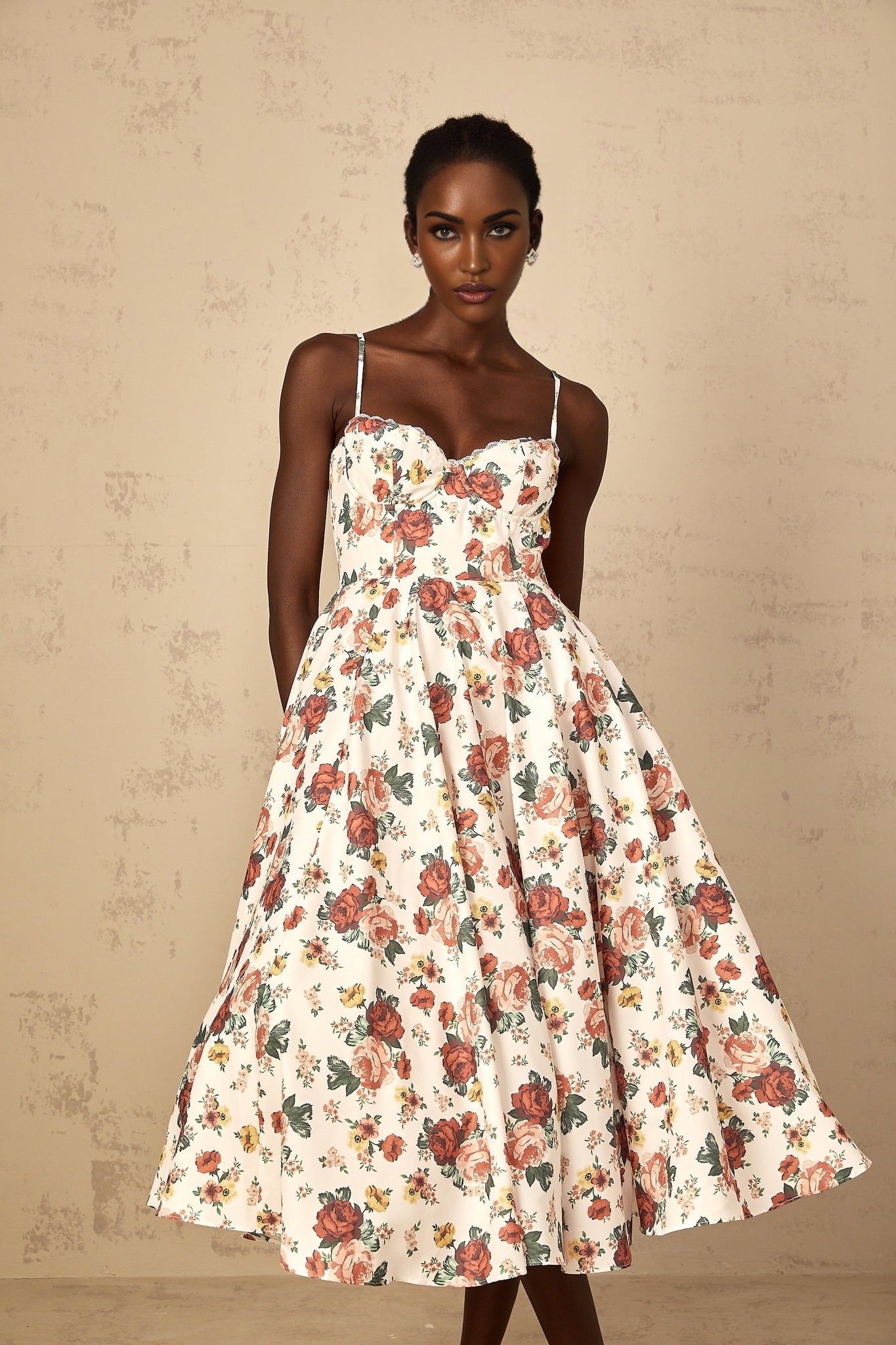 A white midi dress with a rose print pattern featuring flounced details worn by a woman