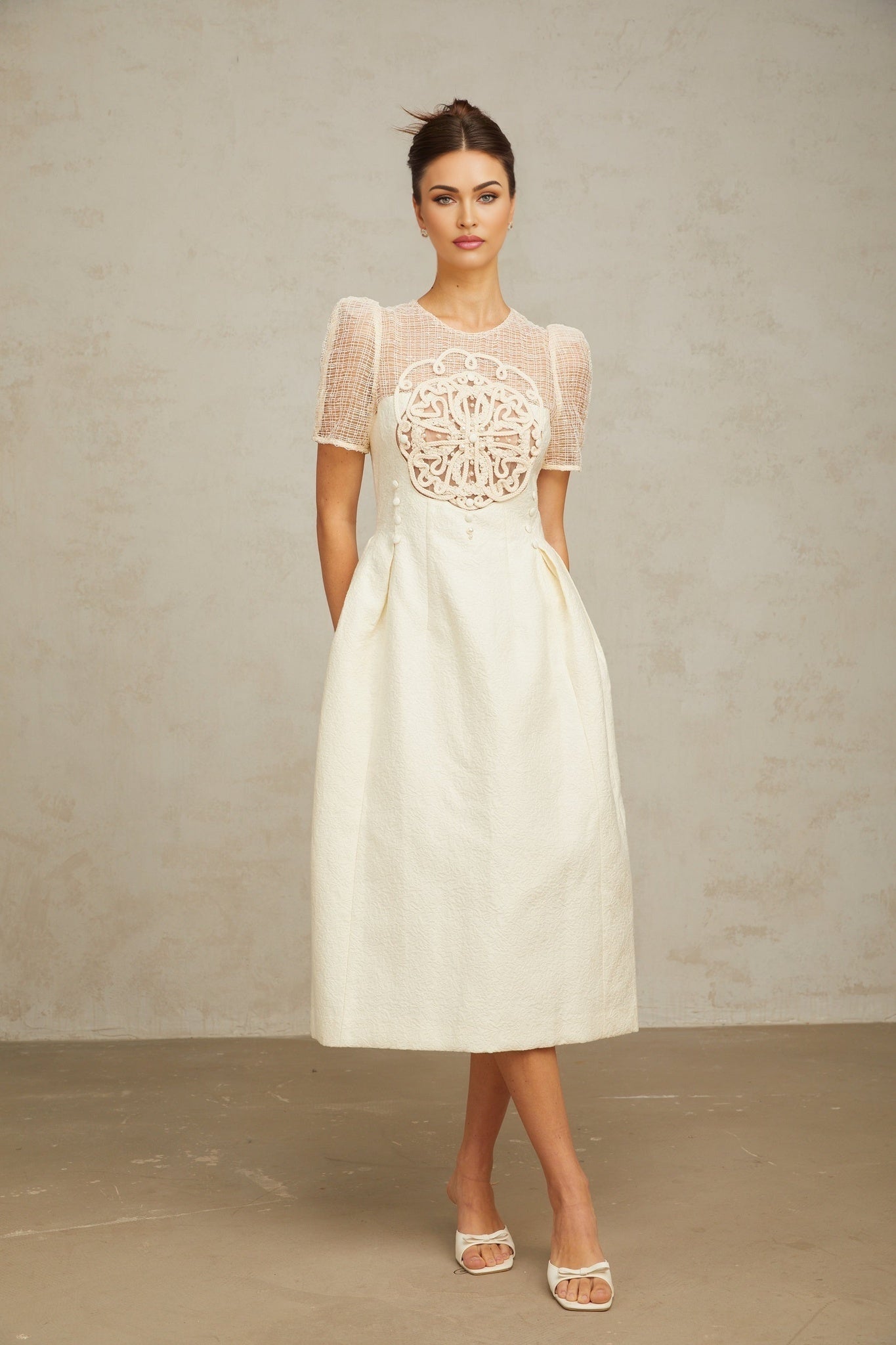 A white midi dress with braided panel details and a fitted silhouette on a female model