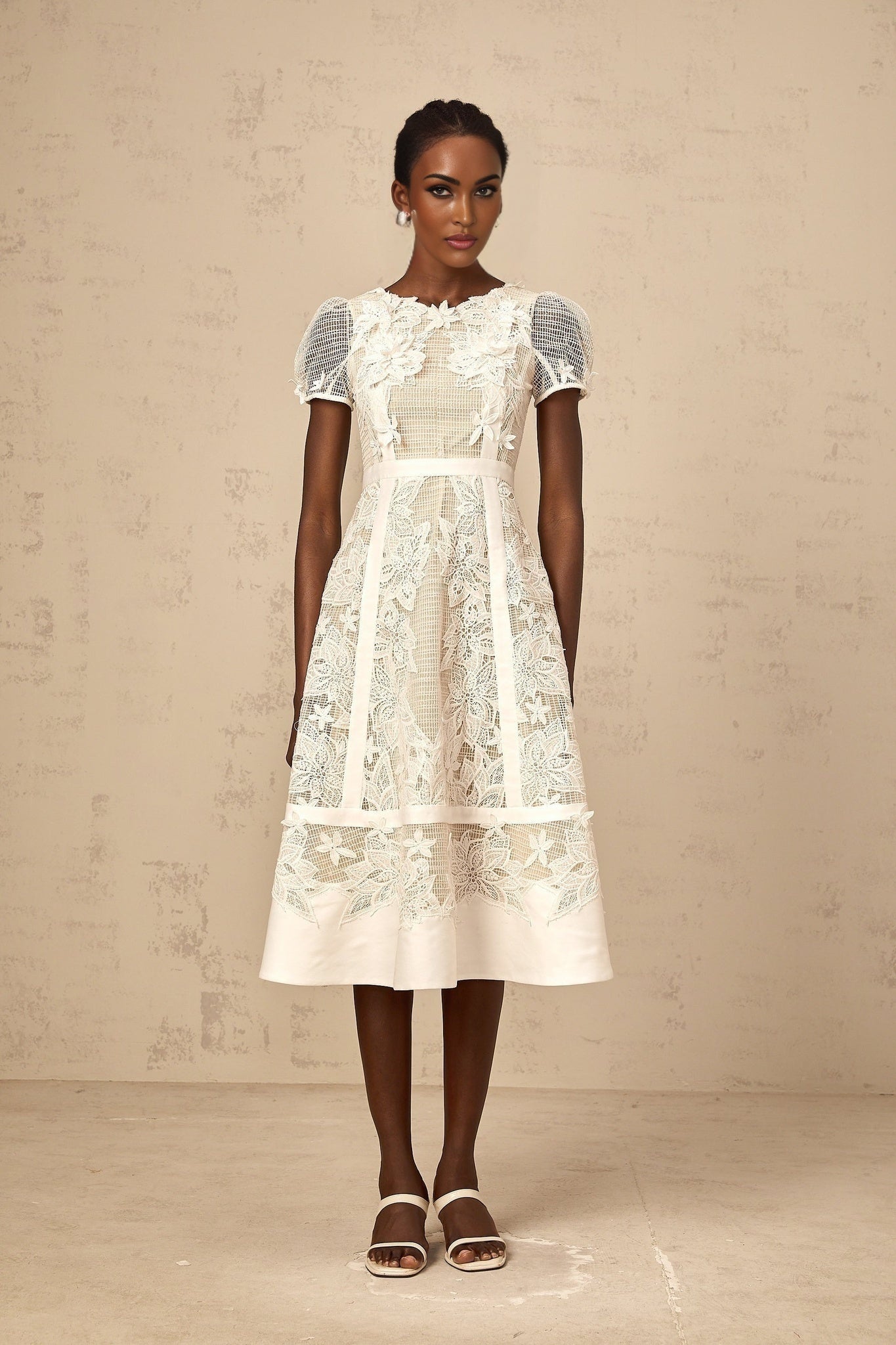 A white midi dress with delicate flower embroidery featuring a feminine silhouette and intricate floral details