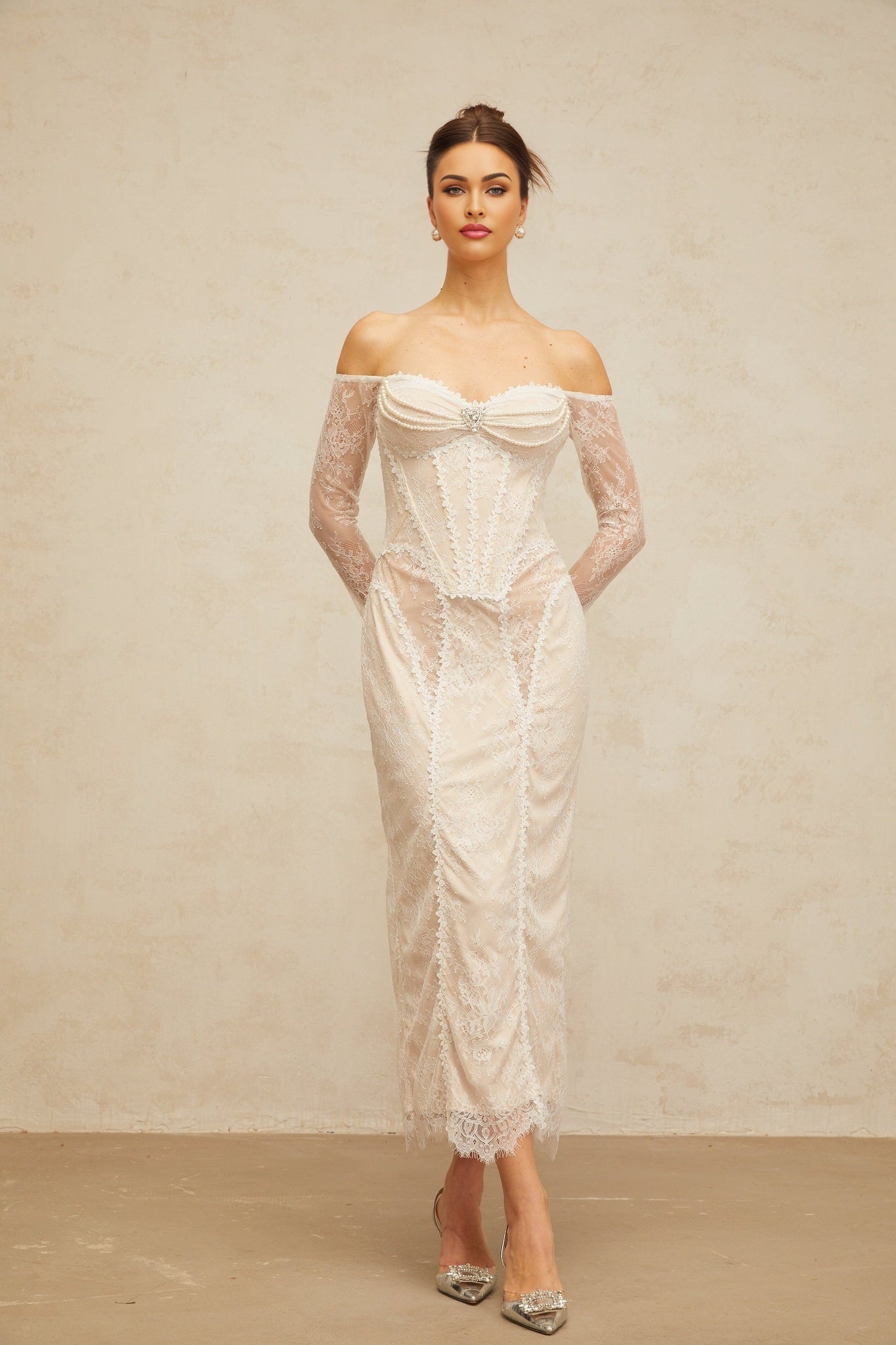 A white midi dress with floral lace embellishments named Enora shown on a model against a plain background