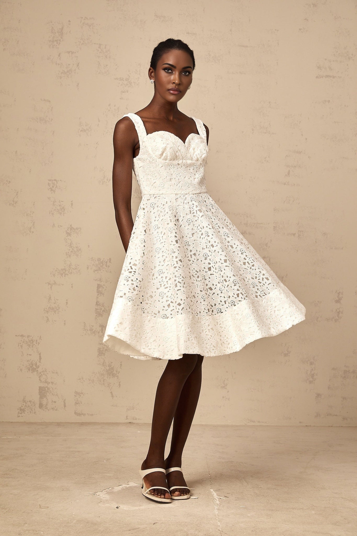 A white midi dress with floral lace pattern featuring a fitted bodice and flowing skirt