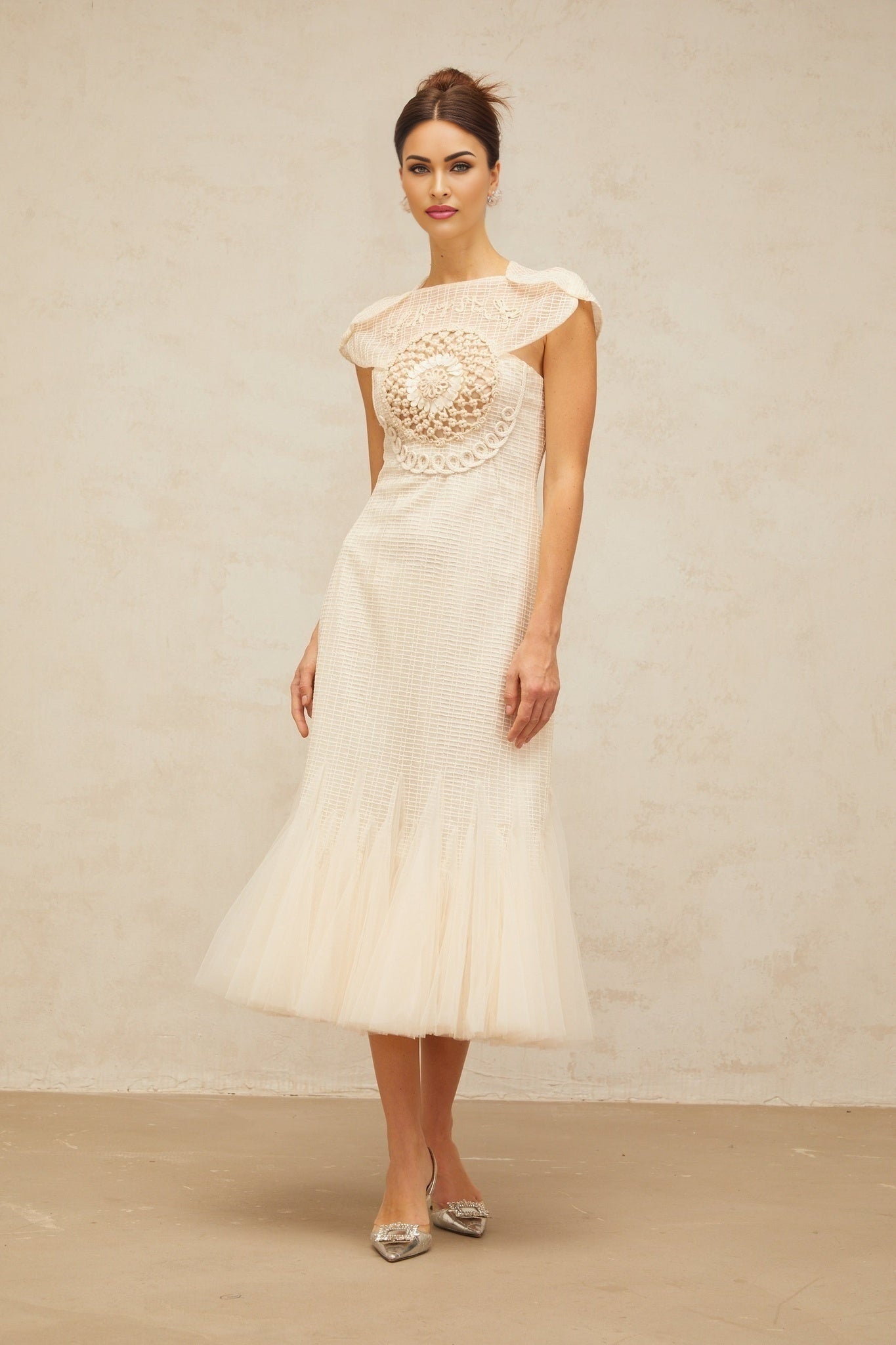 A white midi dress with jacquard pattern and tulle panels styled on a mannequin against a plain background