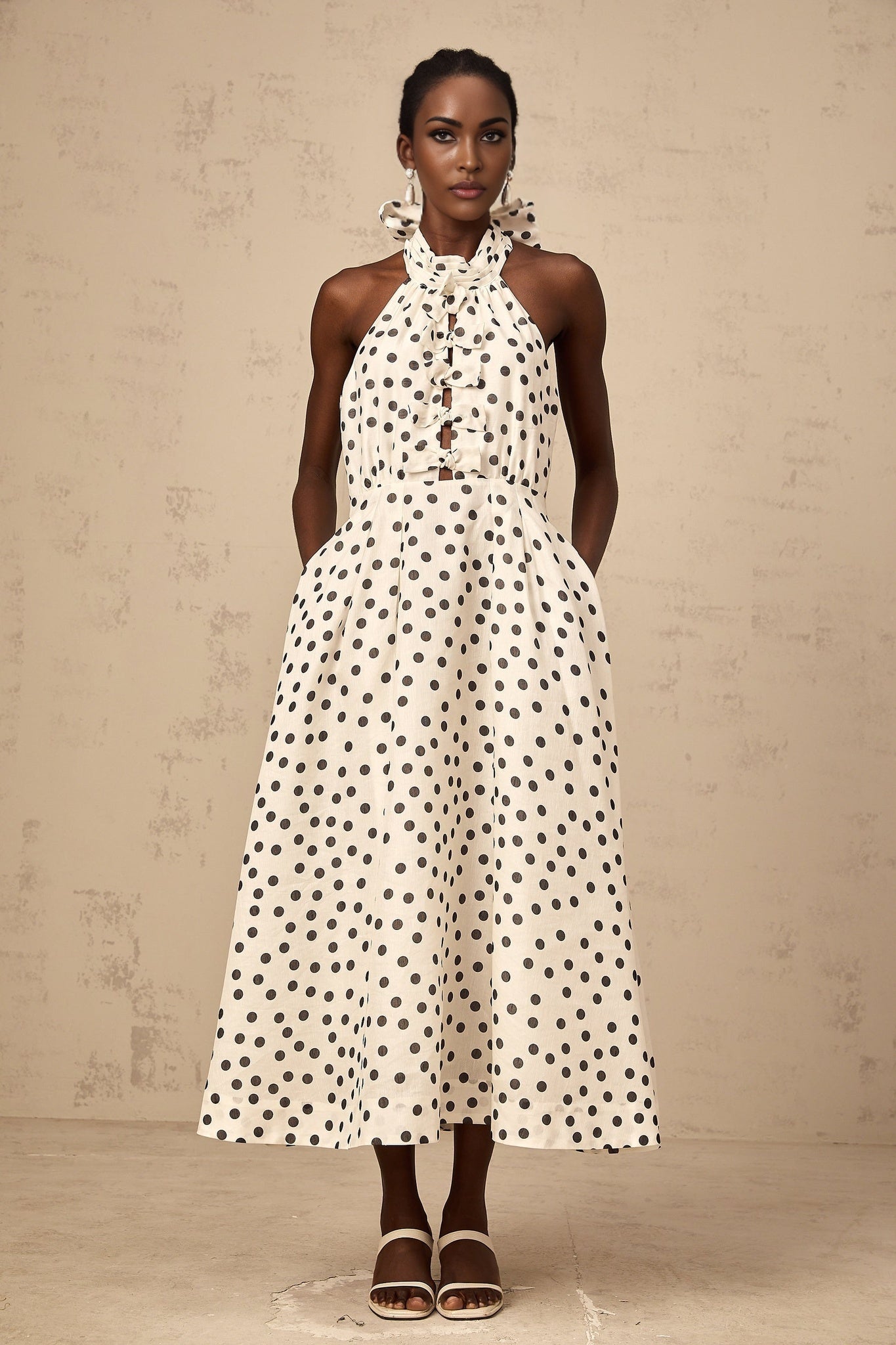 A white midi dress with polka dots and a bow accent named Audrey