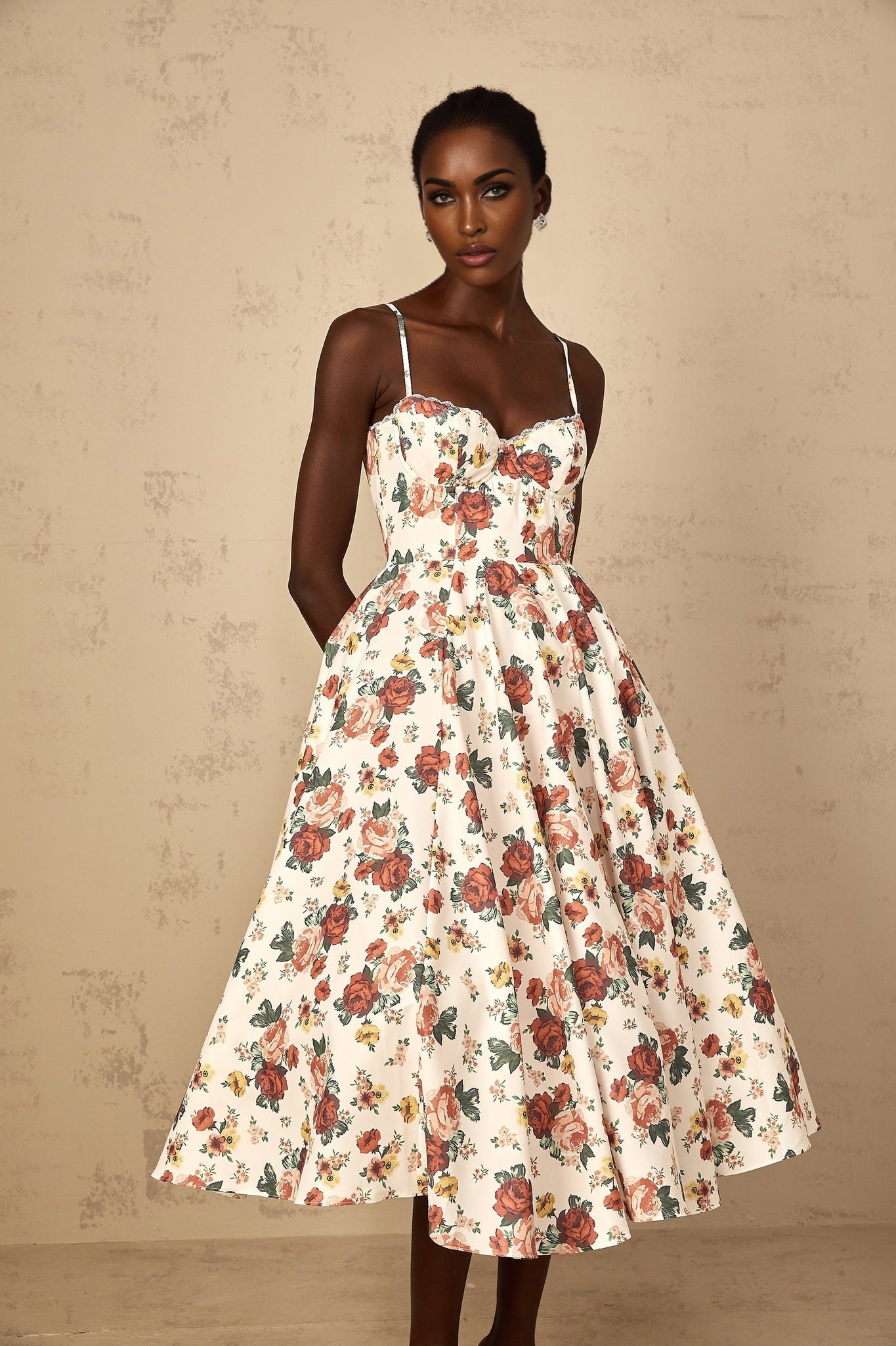 A white midi dress with rose print pattern and flounced details worn by a woman