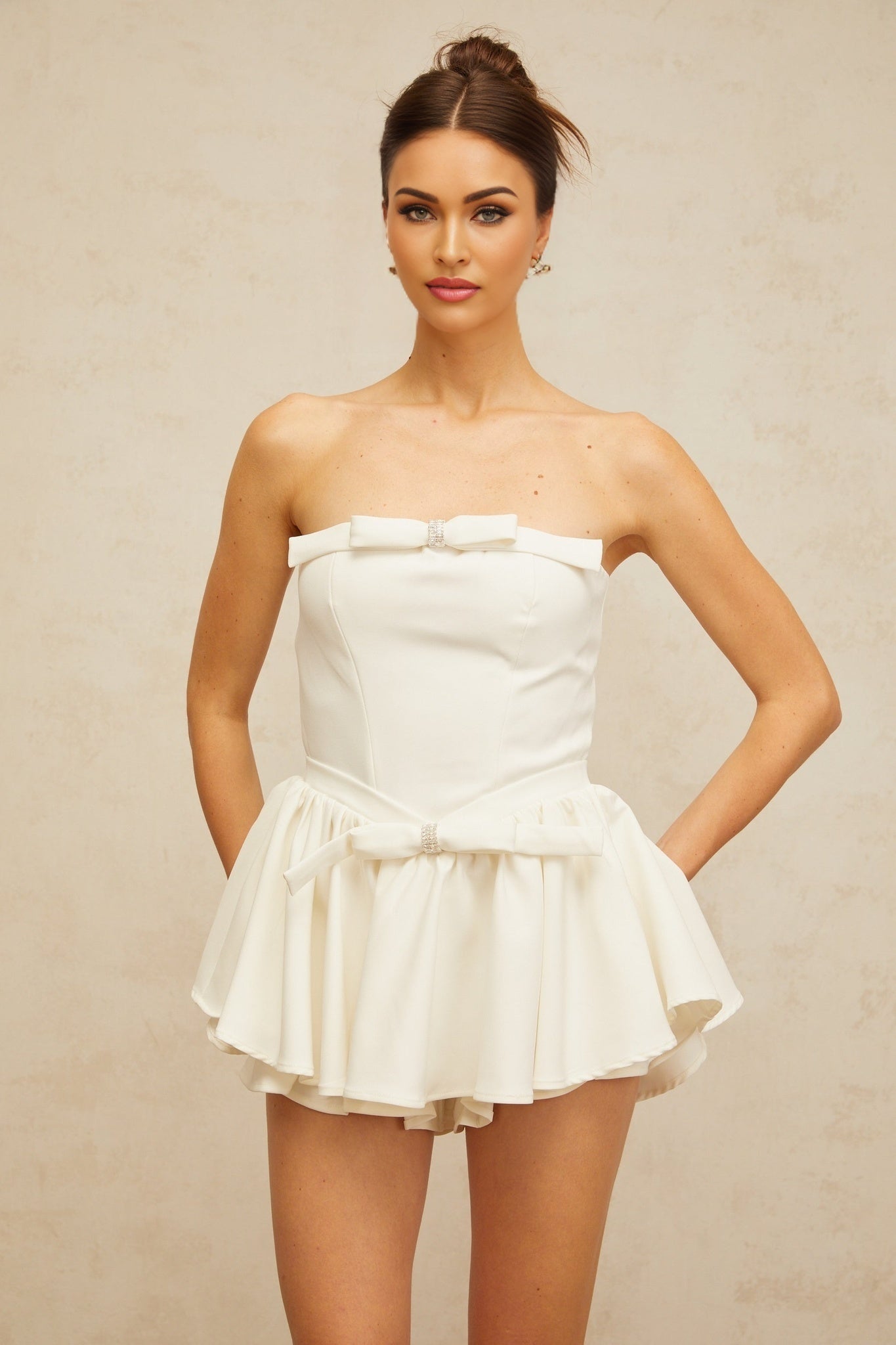 A white mini dress with a corsetstyle bodice featuring a bowknot detail at the front named Ariel