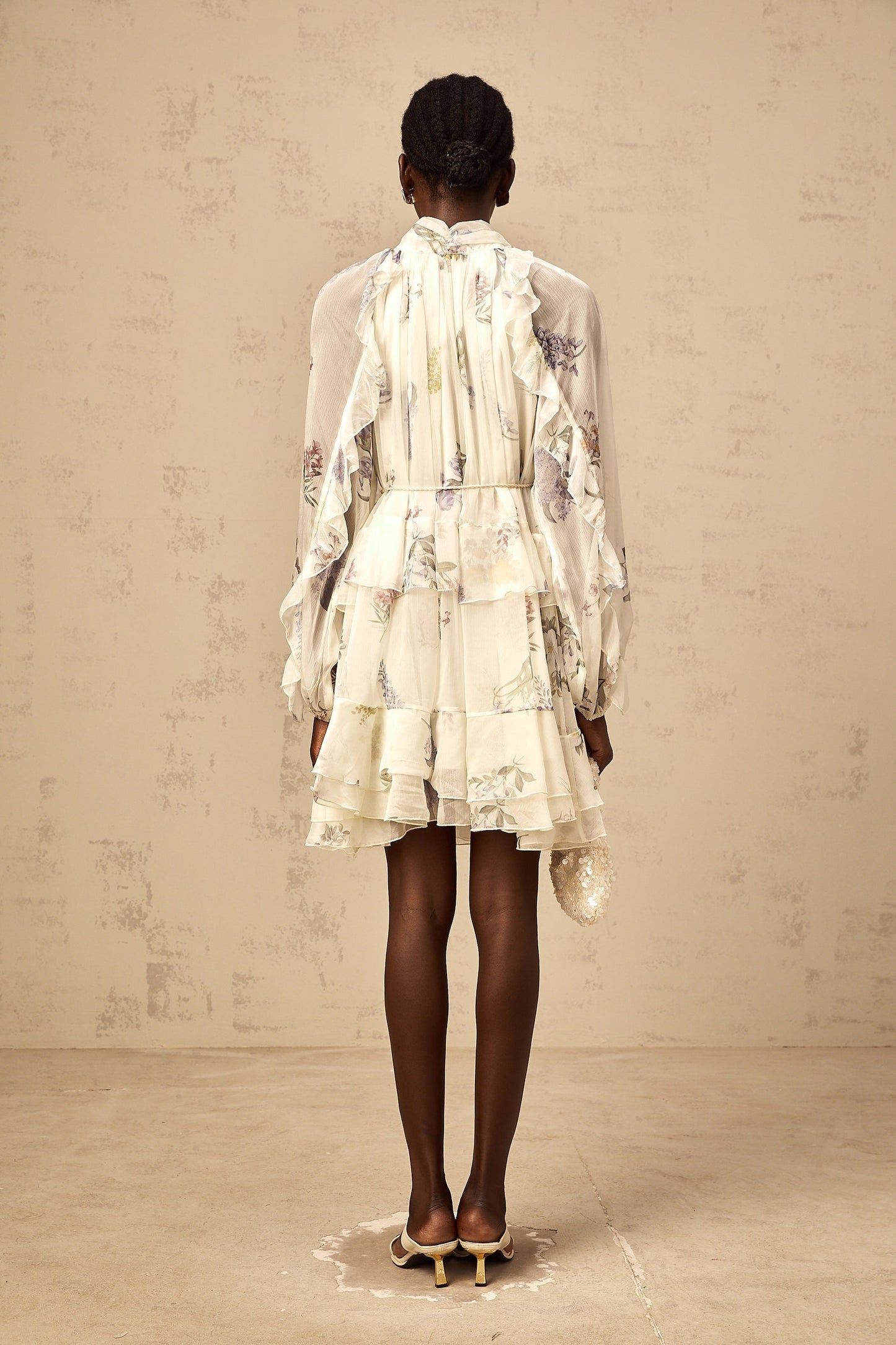 A white mini dress with a floral print pattern made of tiered chiffon fabric featuring a short length and light airy design