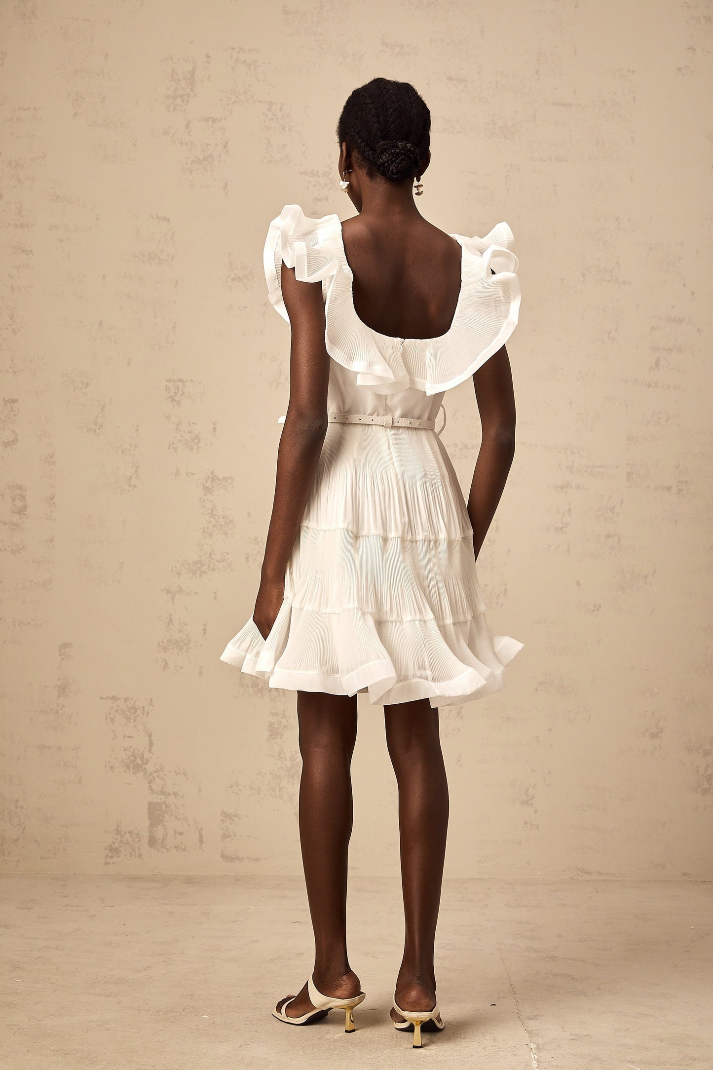A white mini dress with a frilled neckline and pleated design named Éliane