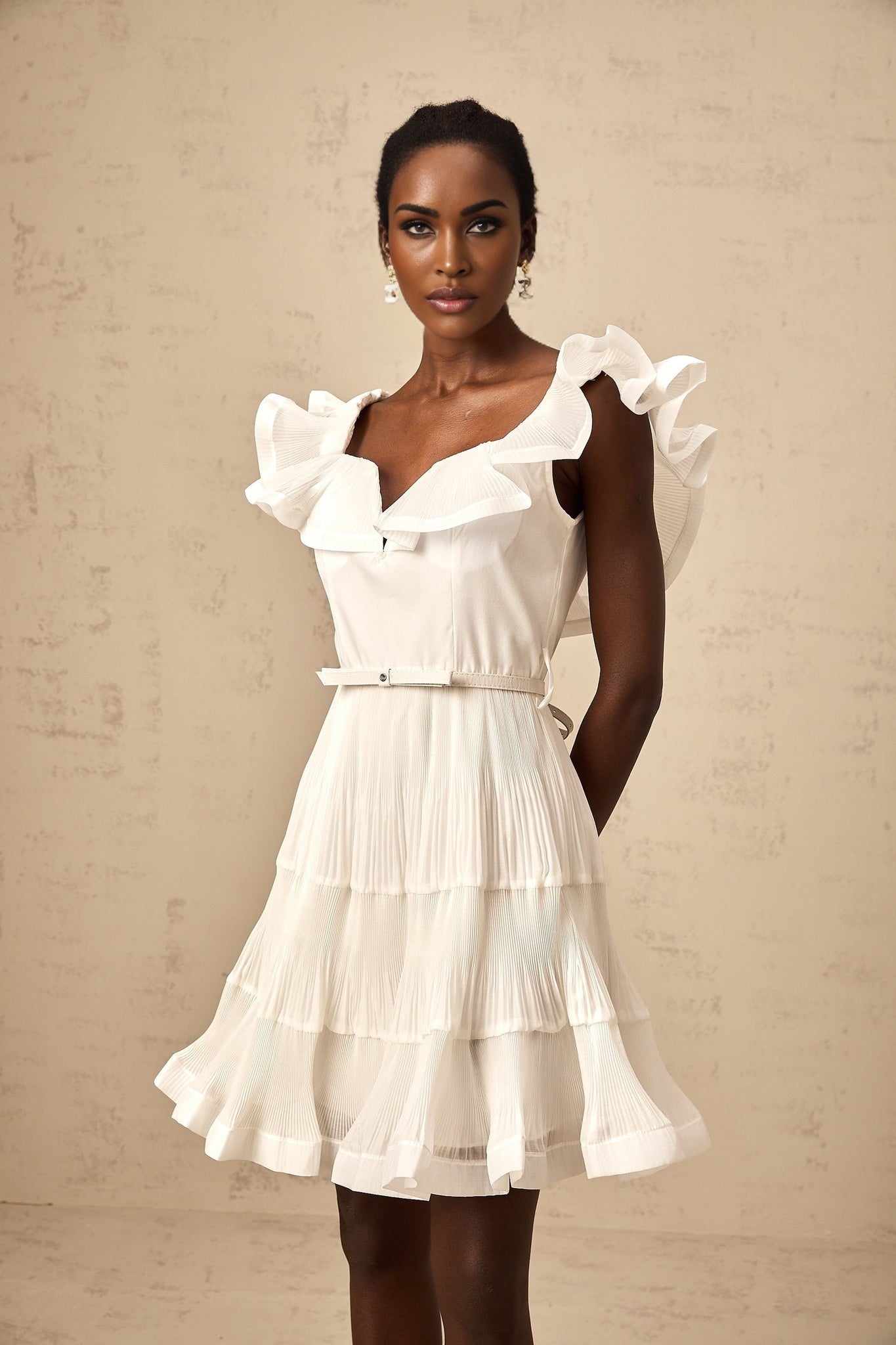A white mini dress with a frilled neckline and pleated design named Eliane