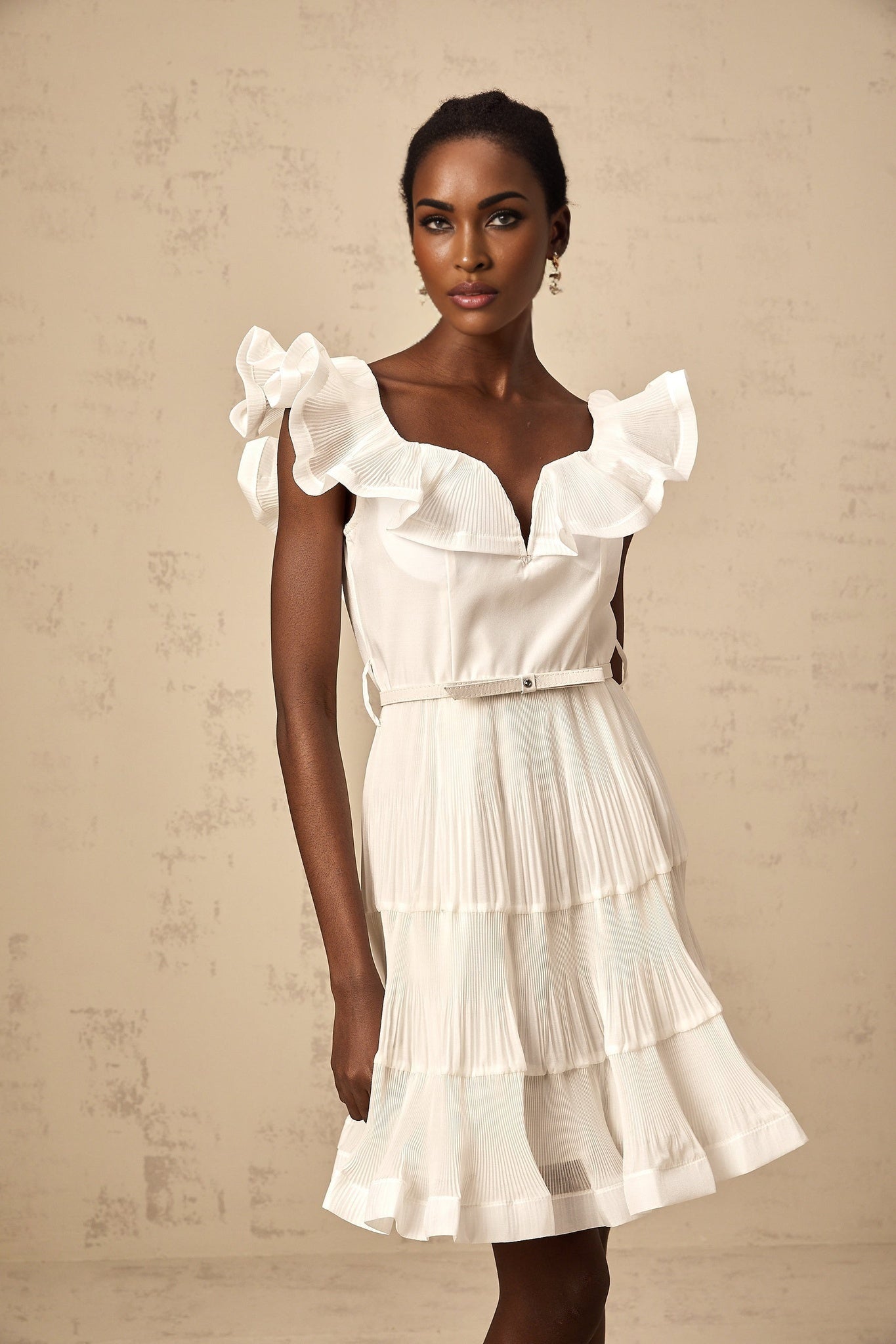 A white mini dress with a frilled neckline and pleated design named Eliane