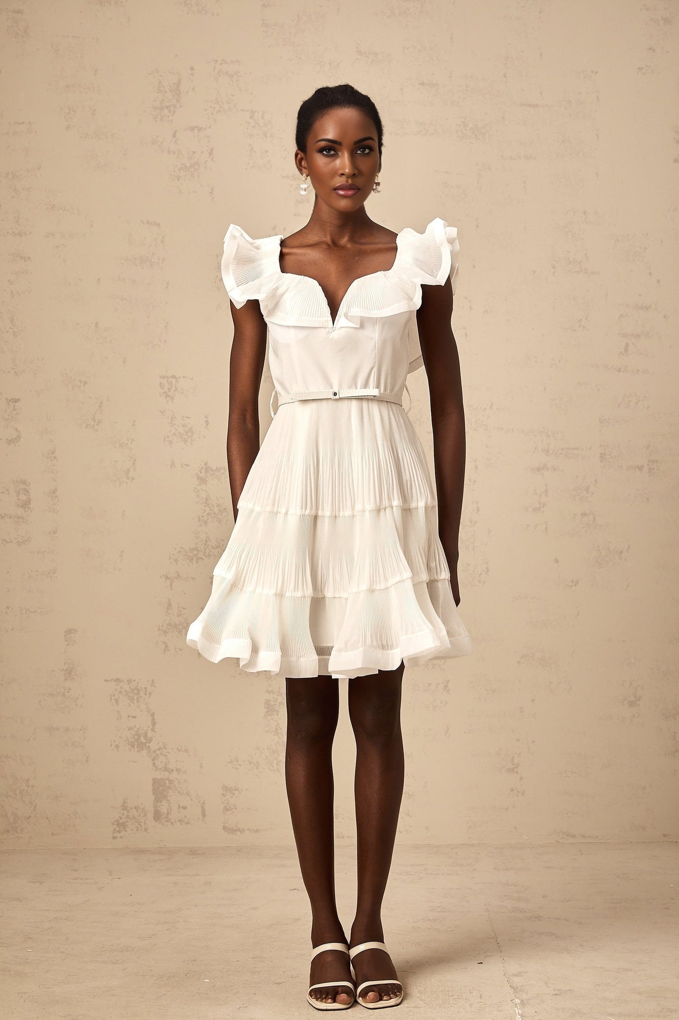 A white mini dress with a frilled neckline and pleated design named Éliane