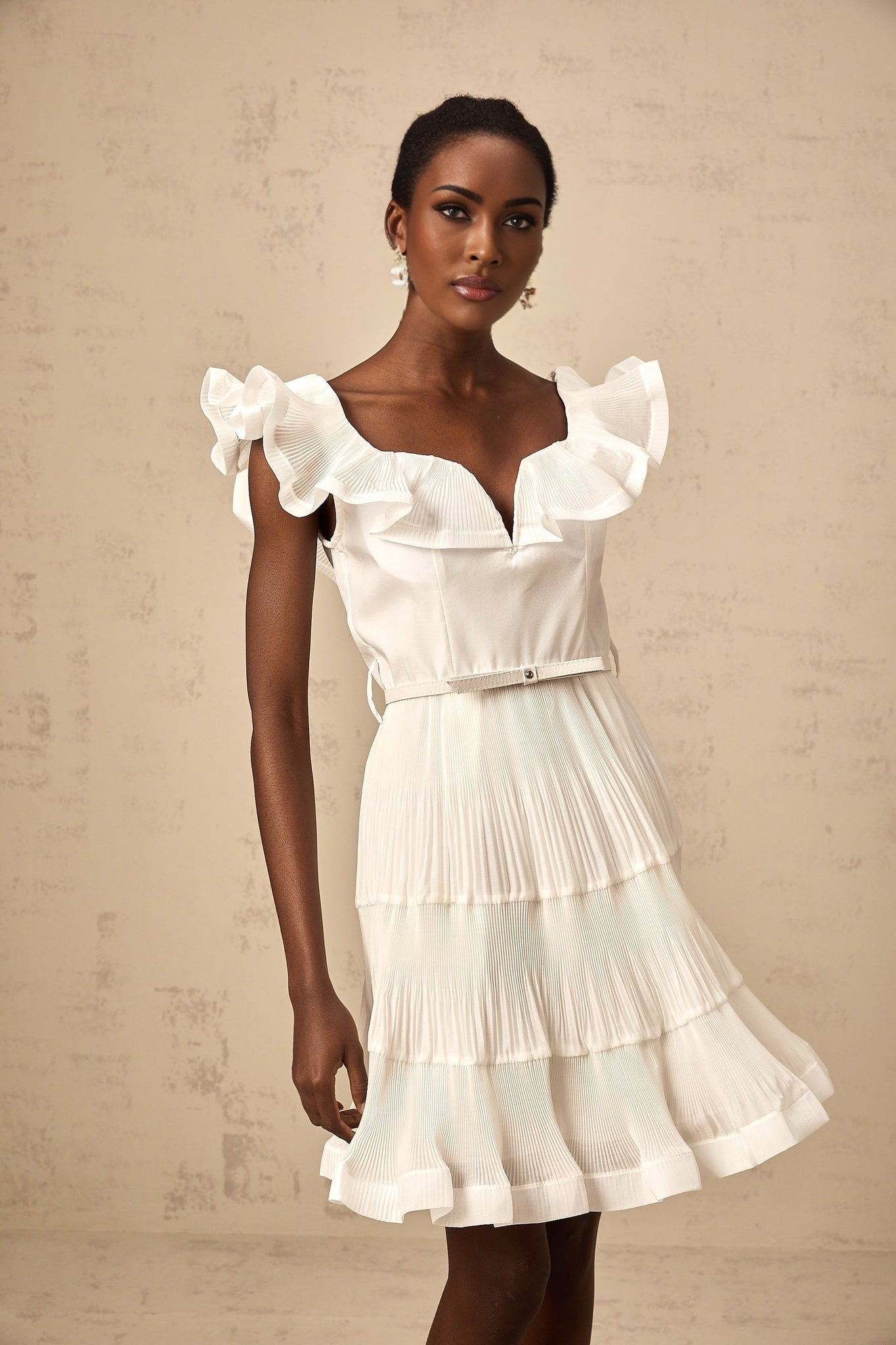 A white mini dress with a frilled neckline and pleated design named Eliane