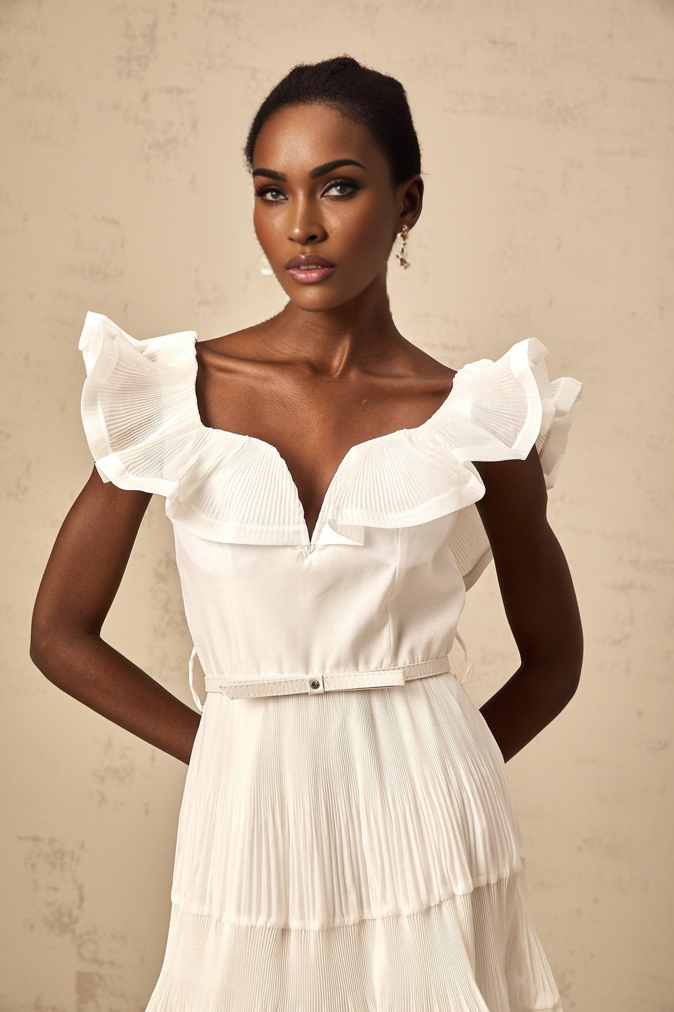 A white mini dress with a frilled neckline and pleated design named Eliane