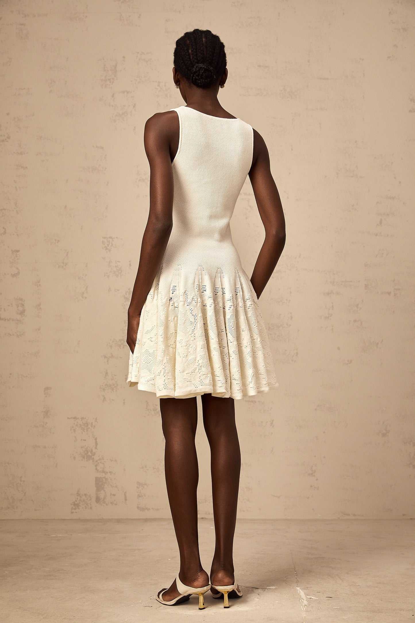 A white mini dress with a jacquard knit pattern featuring a short hemline and textured fabric design