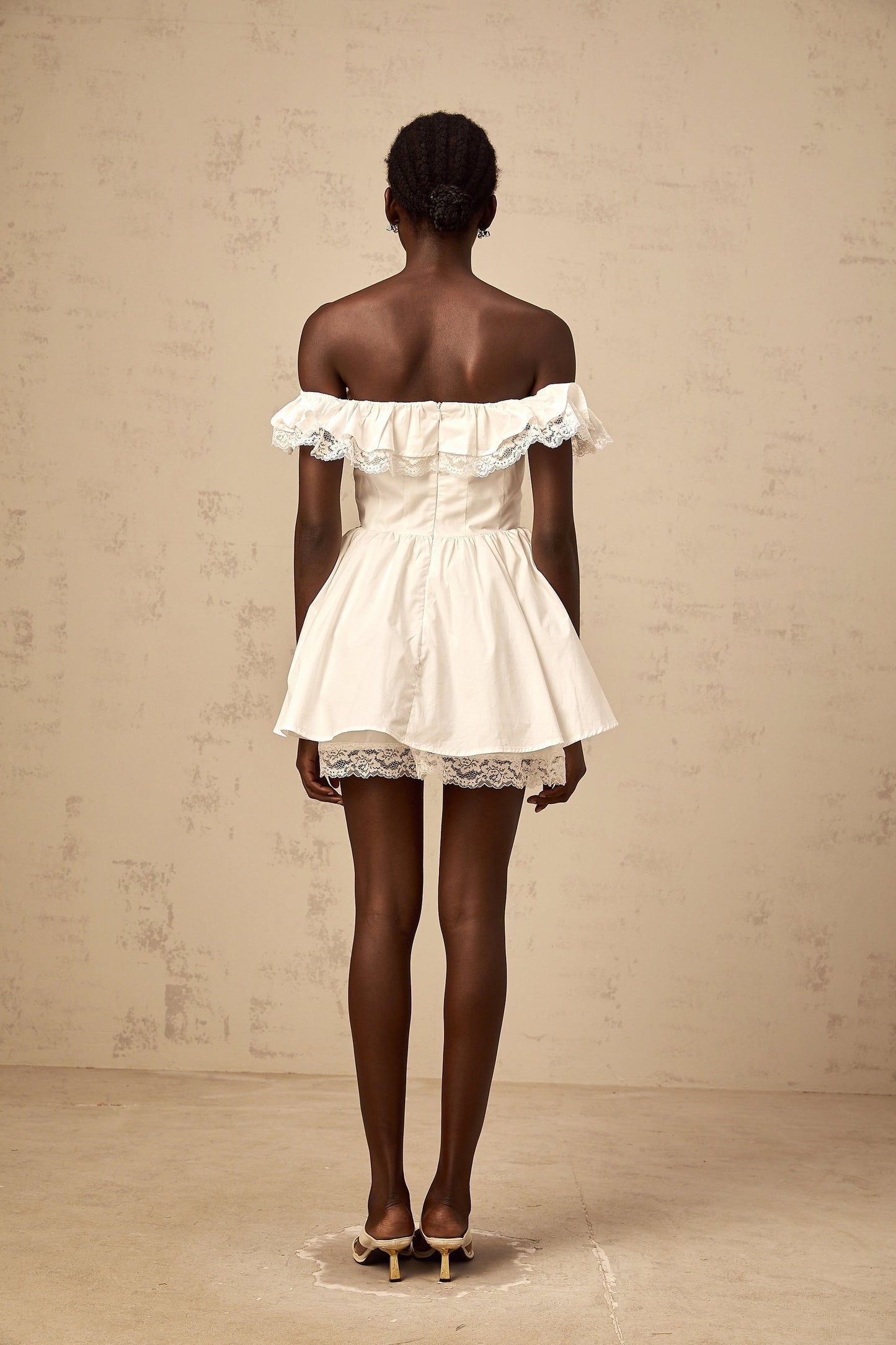 A white mini dress with an oversized bow and ruffle details featuring a short hemline and feminine silhouette