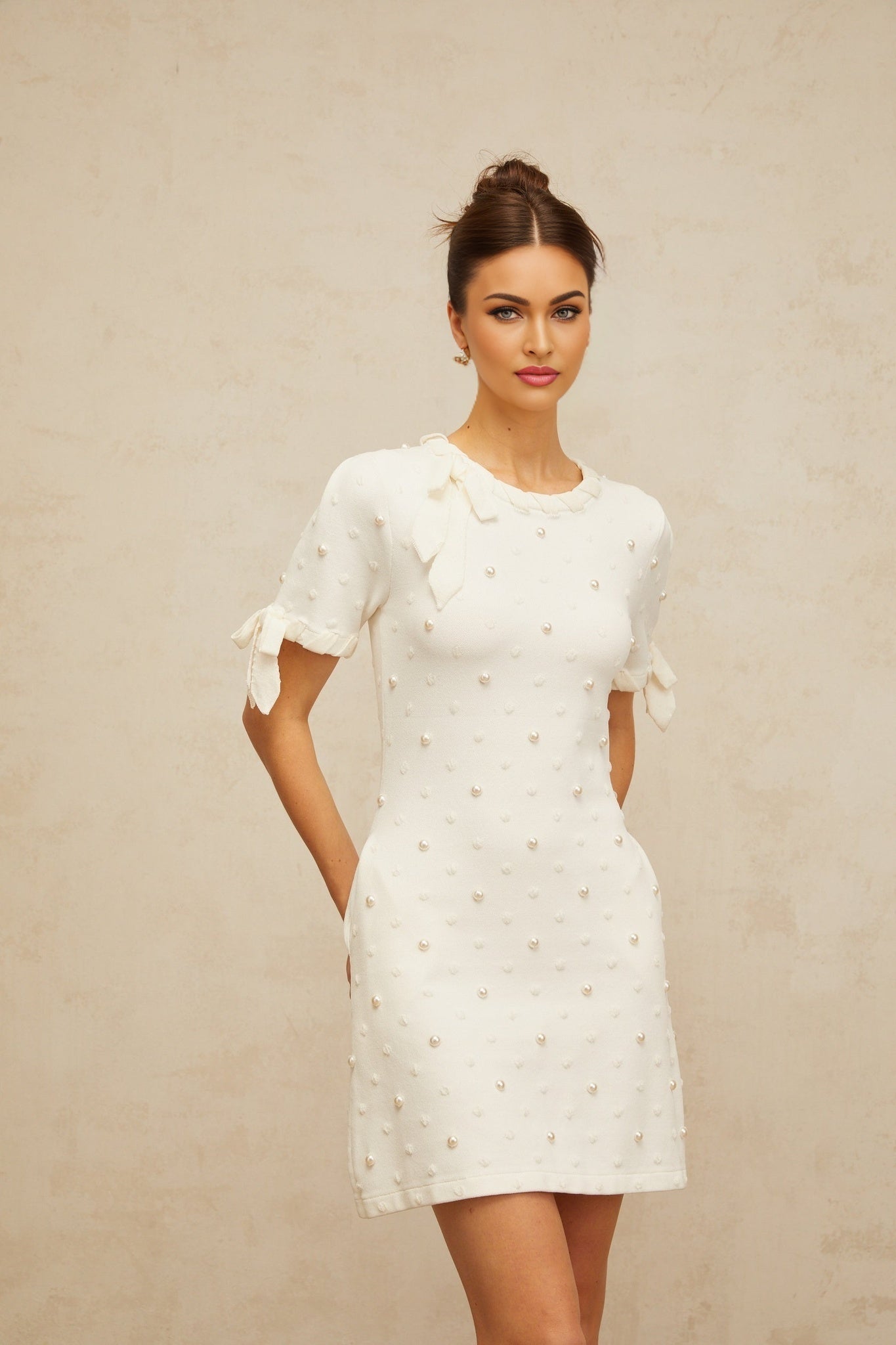 A white mini dress with black polka dots and heart patterns knitted into the fabric featuring short sleeves and a fitted silhouette