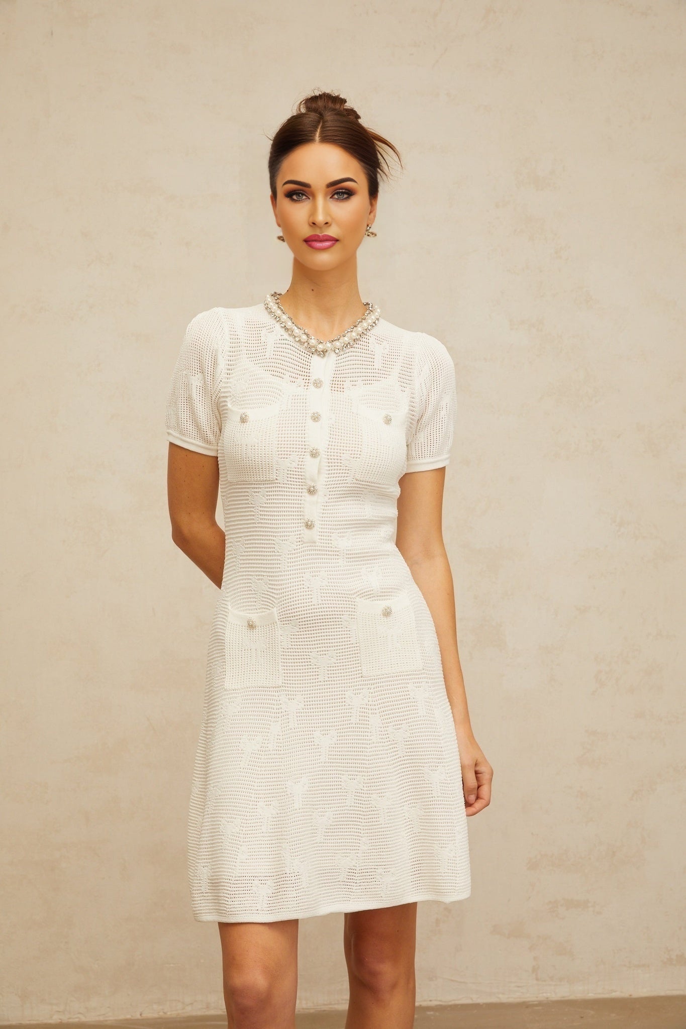 A white mini dress with crochet knit pattern and embellishments featuring a delicate Marjolaine design