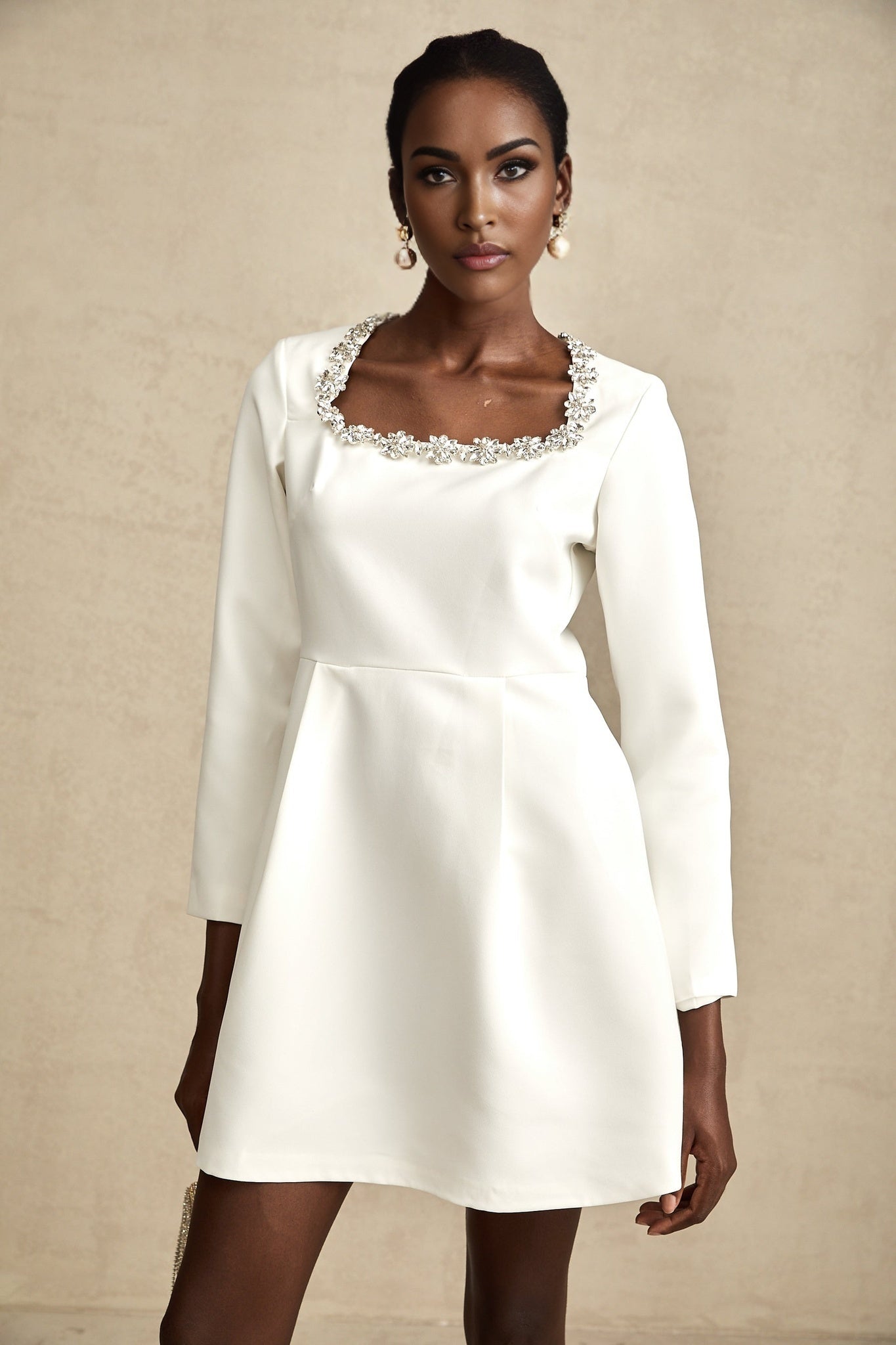 A white mini dress with crystal embellishments featuring an Aline silhouette and the name Angelique