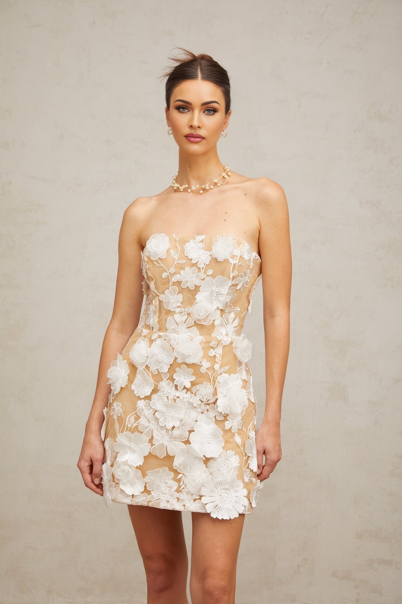 A white mini dress with floral applique details featuring a design inspired by Veronica flowers